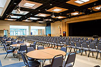 Gaiser student center showing tables in back of room and chairs arranged in rows in the front of the room, facing the stage.