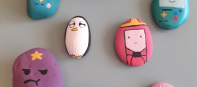 Rocks painted with faces and mounted on a wall.