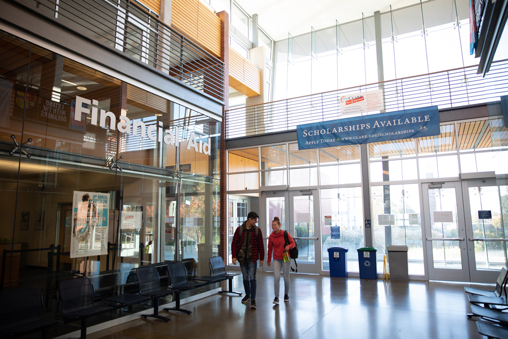 Two students walking through Gaiser Hall past the Financial Aid Office sign.