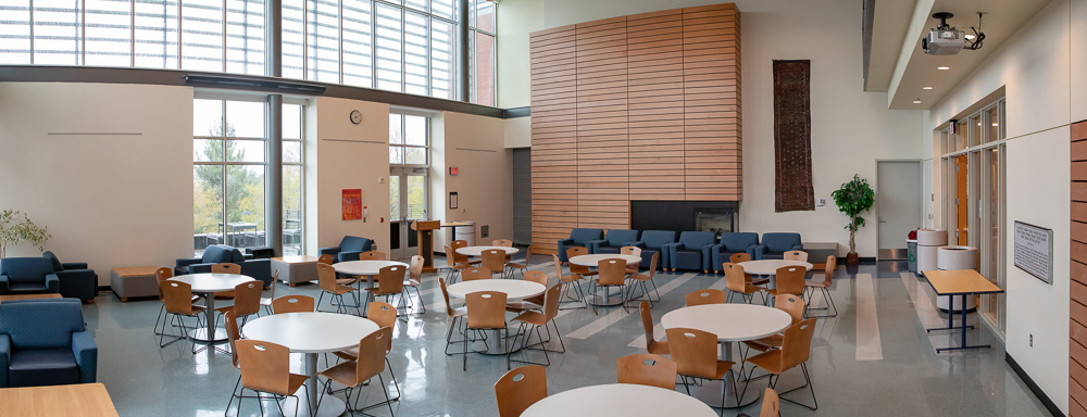 photo of Penguin Union Lounge showing tables with chairs, fireplace wall and large windows spanning two walls.