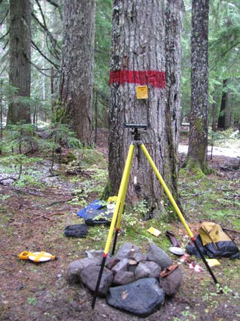 Compass on tripod in wooded area.