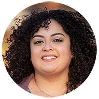 Katia Quinterno close up headshot of a smiling face with curly brown hair. 