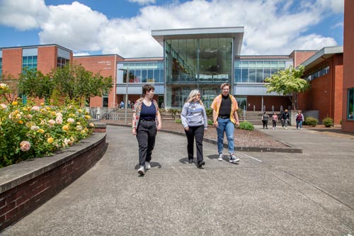 A group of three students walking out from the Gaiser Hall building at Clark College