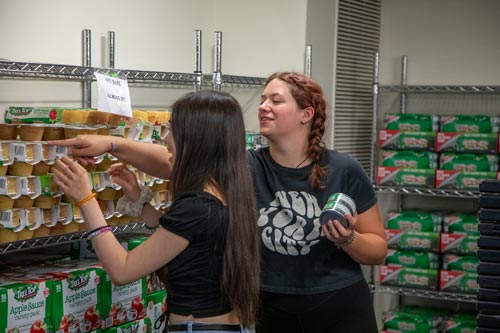 A staff member helping a student reach for an item