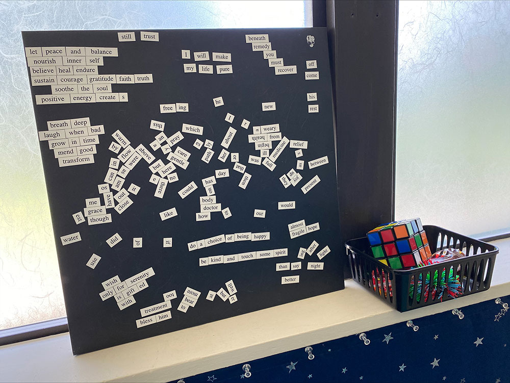 Assembled wordboard with numerous word pieces on slips of paper. Adjacent to it is a mini basket filled with various fidget toys.