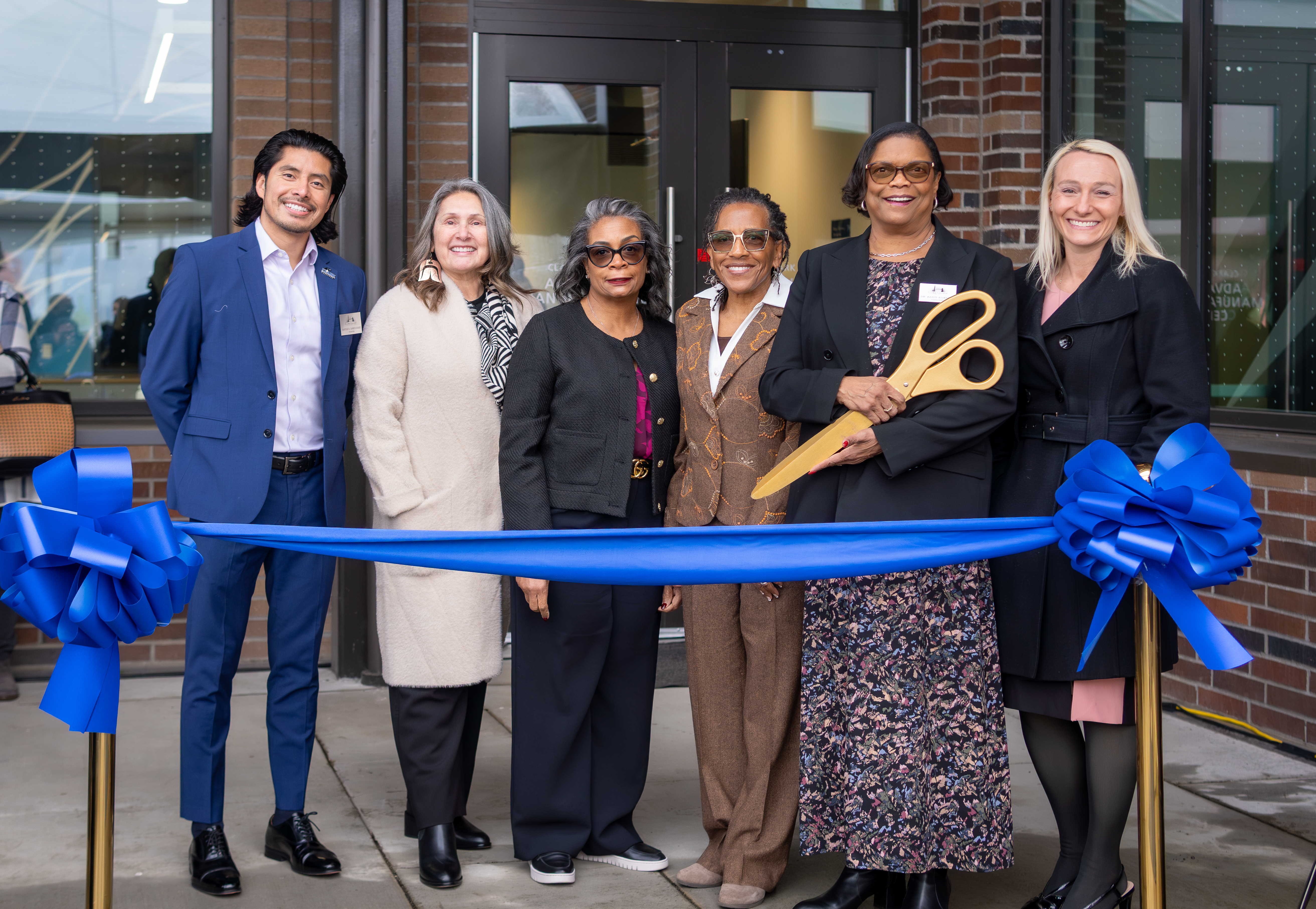 Clark College Board of Trustees with Dr. Edwards stand behind a big blue ribbon at the AMC building.