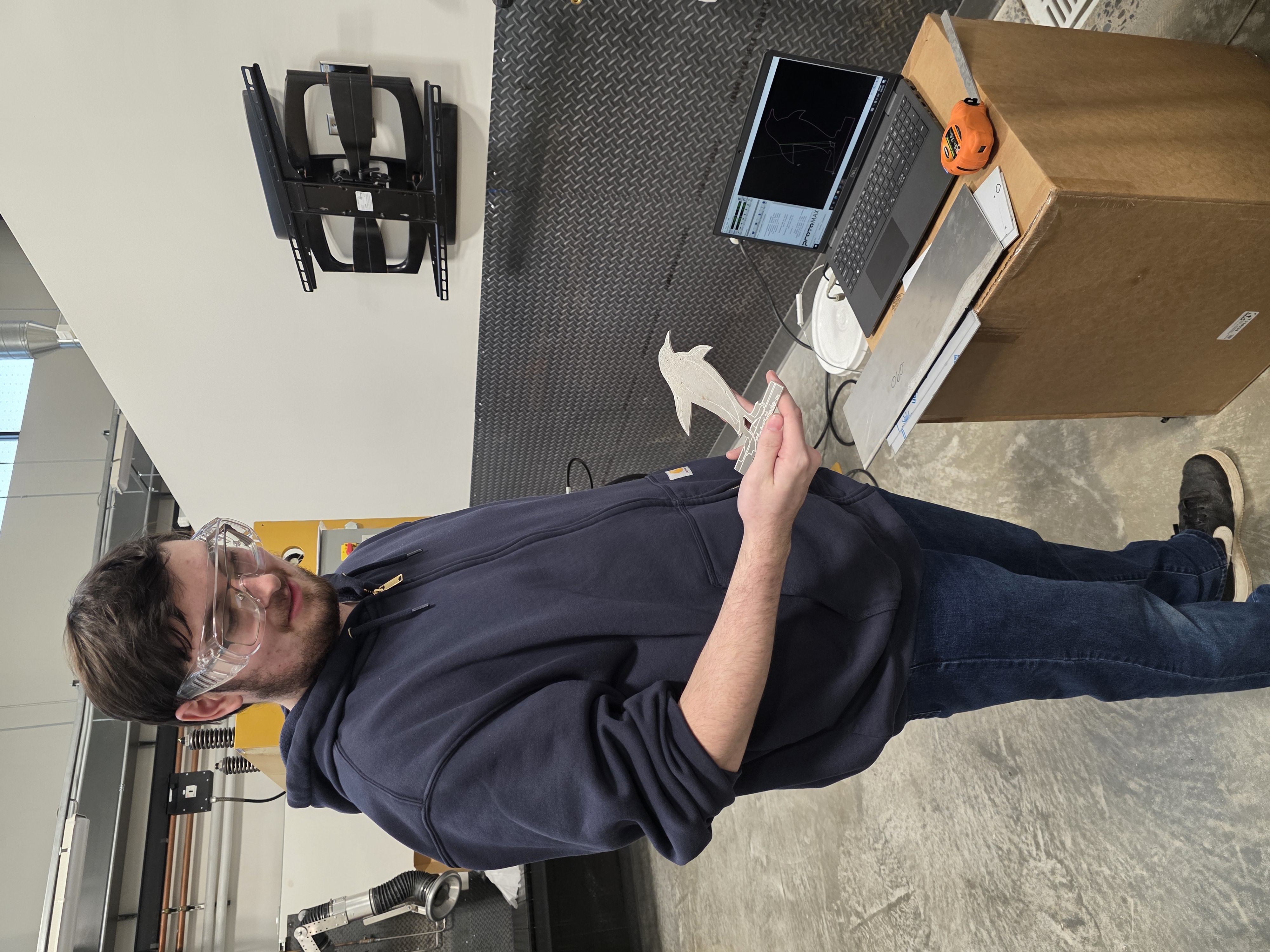 A student wearing goggles holds up a metal penguin