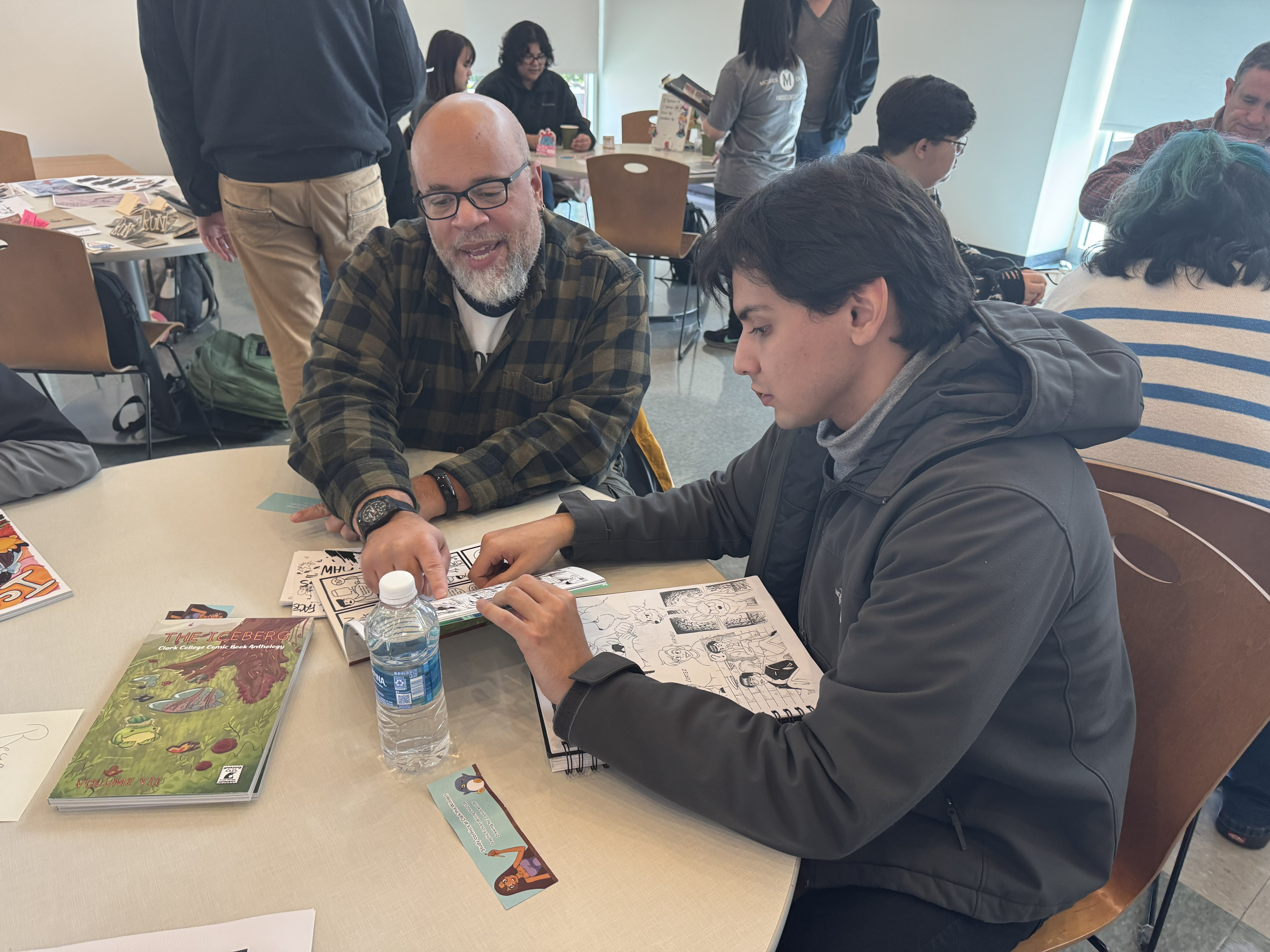 David Walker and a student sit at a table while looking at The Iceberg