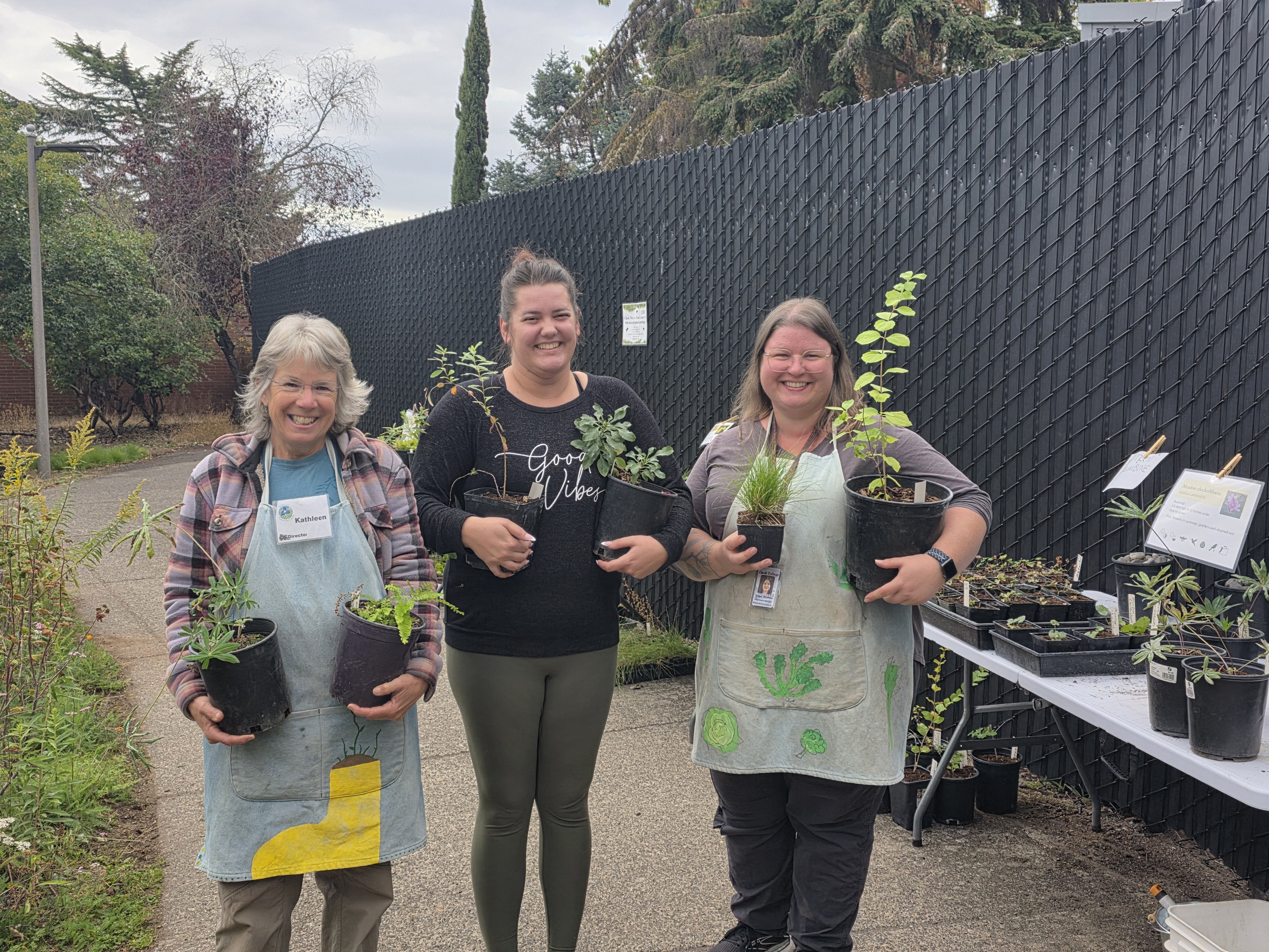 Kathleen, Destiny, and Meg holding plants.
