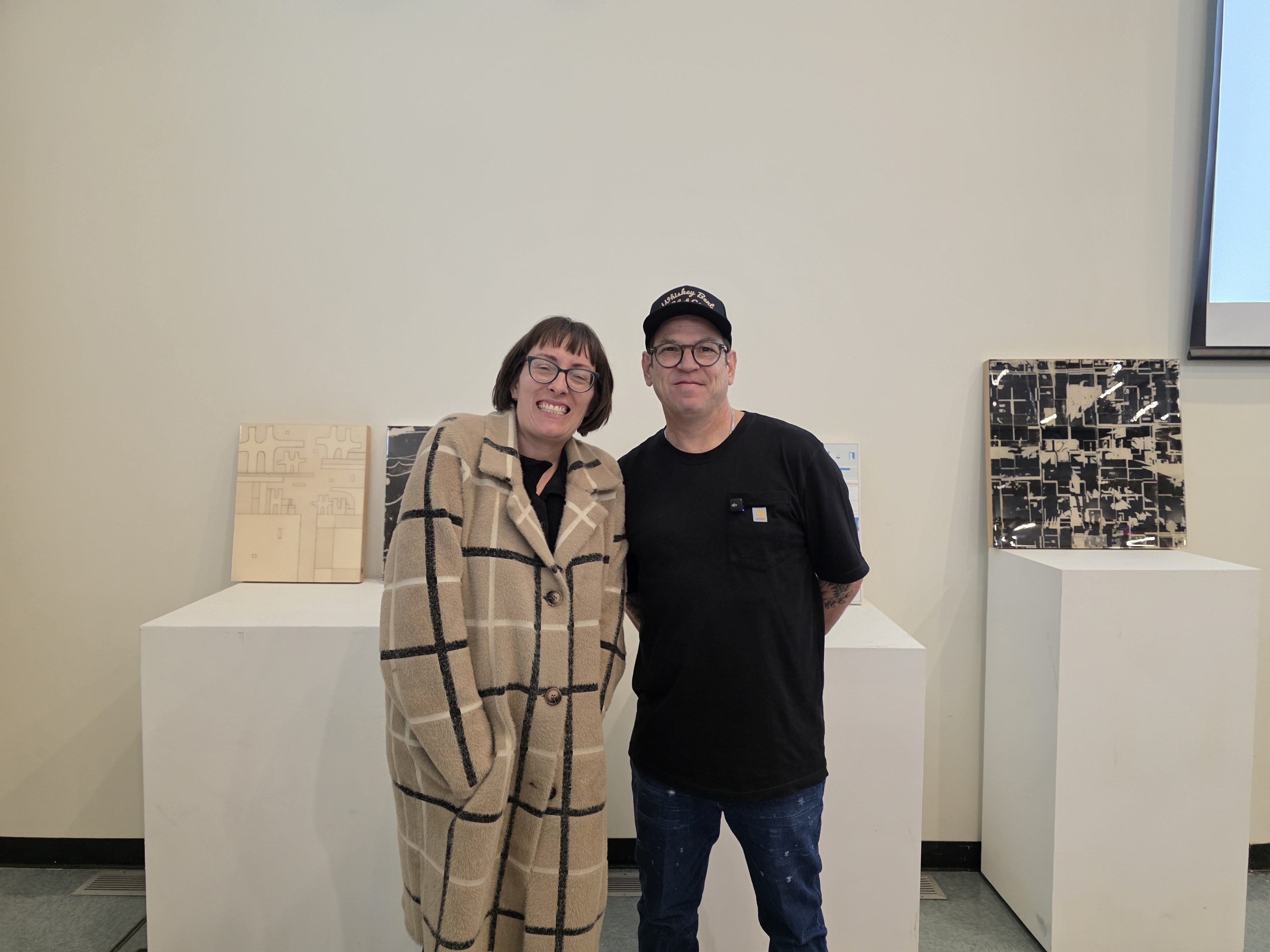 Kendra Larson and visiting artist posing in front of his art