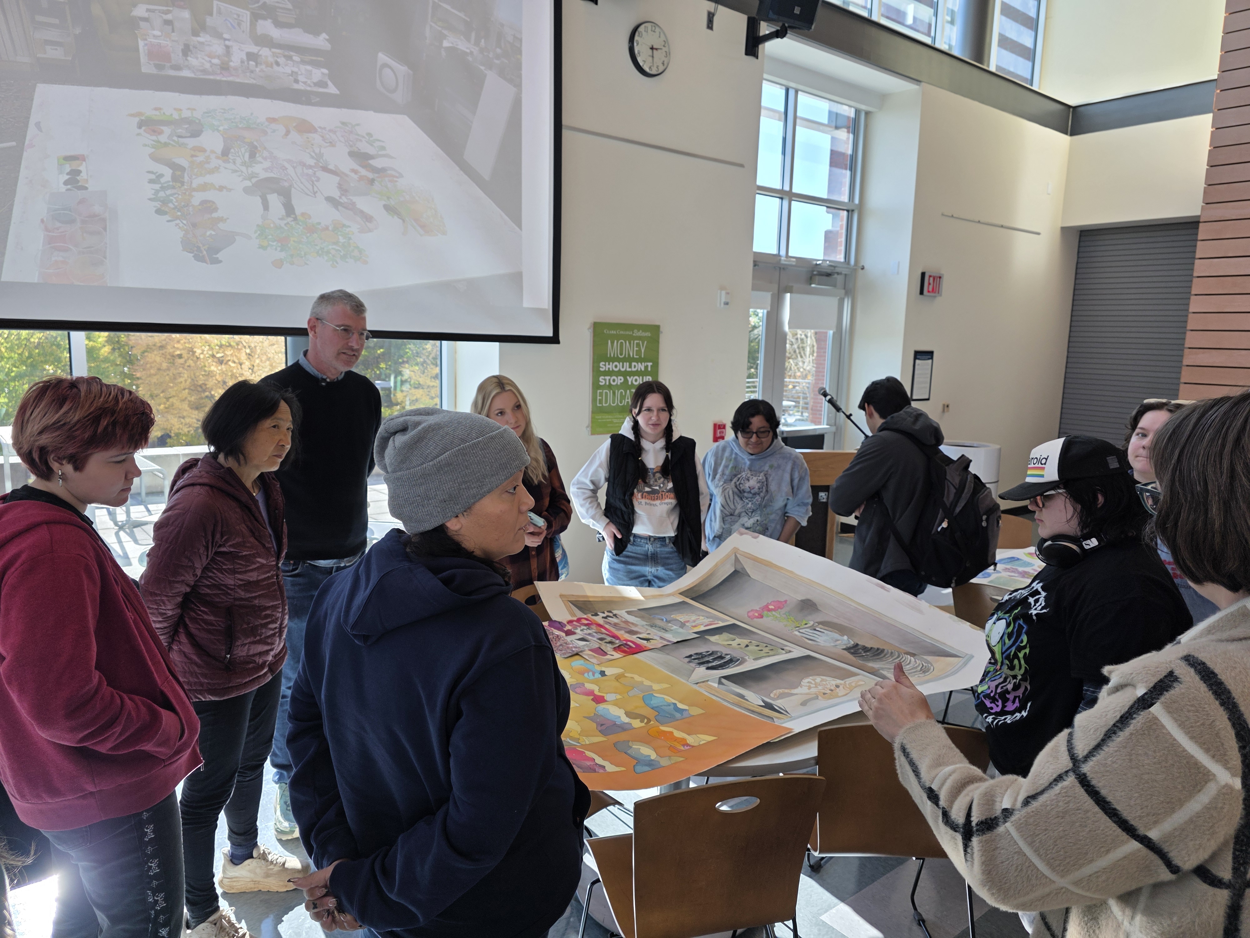 Artist and students gathered around a table covered in art