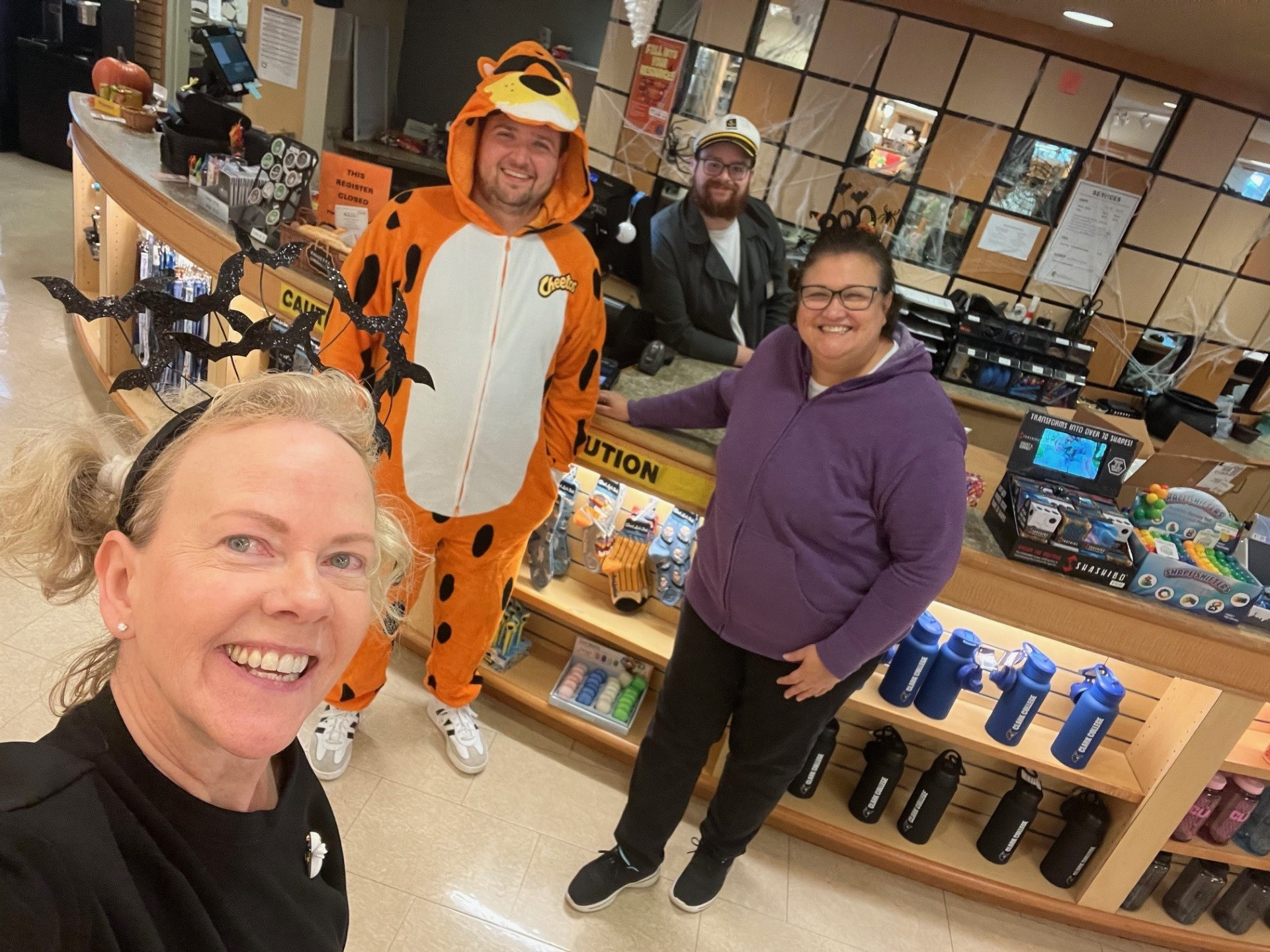 Bookstore staff members in costume at the store counter decorated with cobwebs and bats