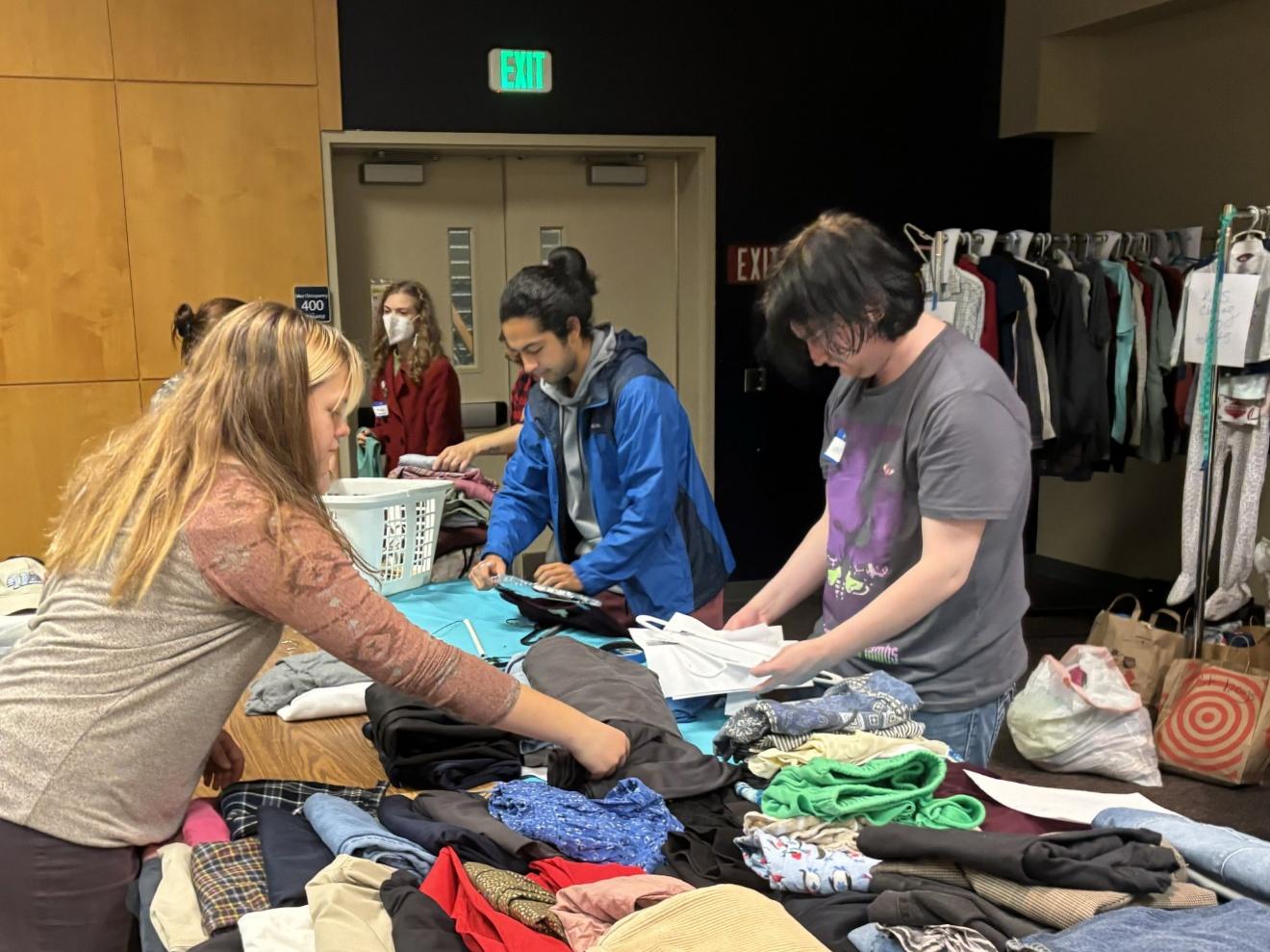 Student volunteers organize clothing on a table