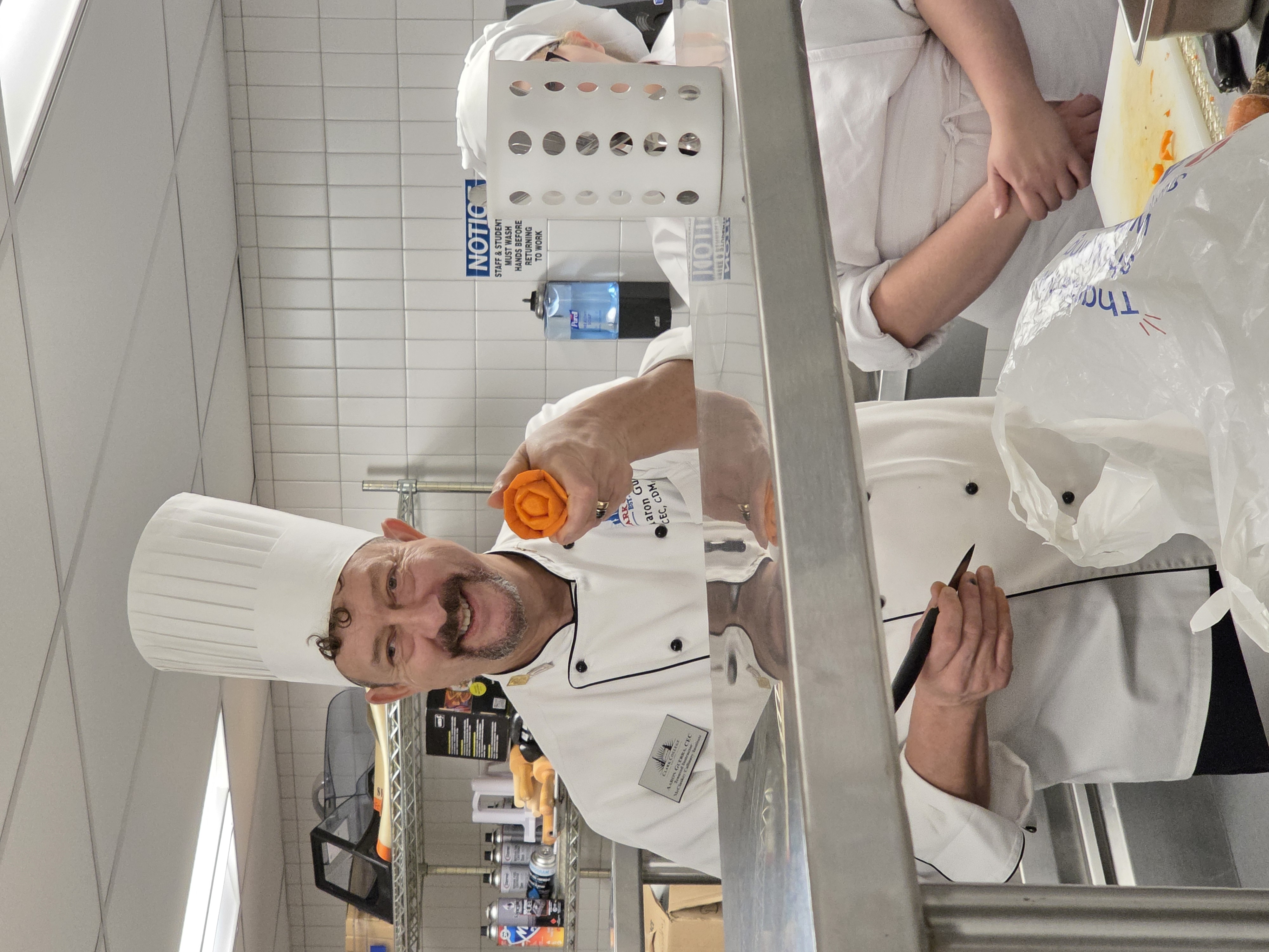 Chef Aaron holds up a carrot carved into a rose