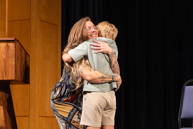 Woman on stage hugging a small boy