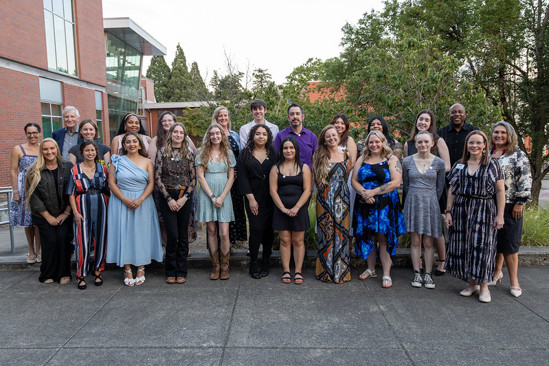 Nineteen students, dressed nicely, standing in rows, posing for a photo