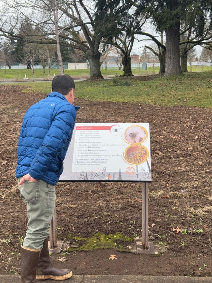 Man looking at sign in front of bee garden on a winter day