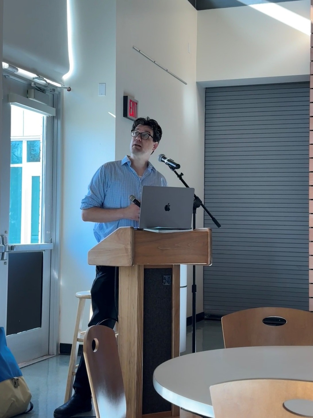 An artist stands at a podium, looking at the screen behind him.