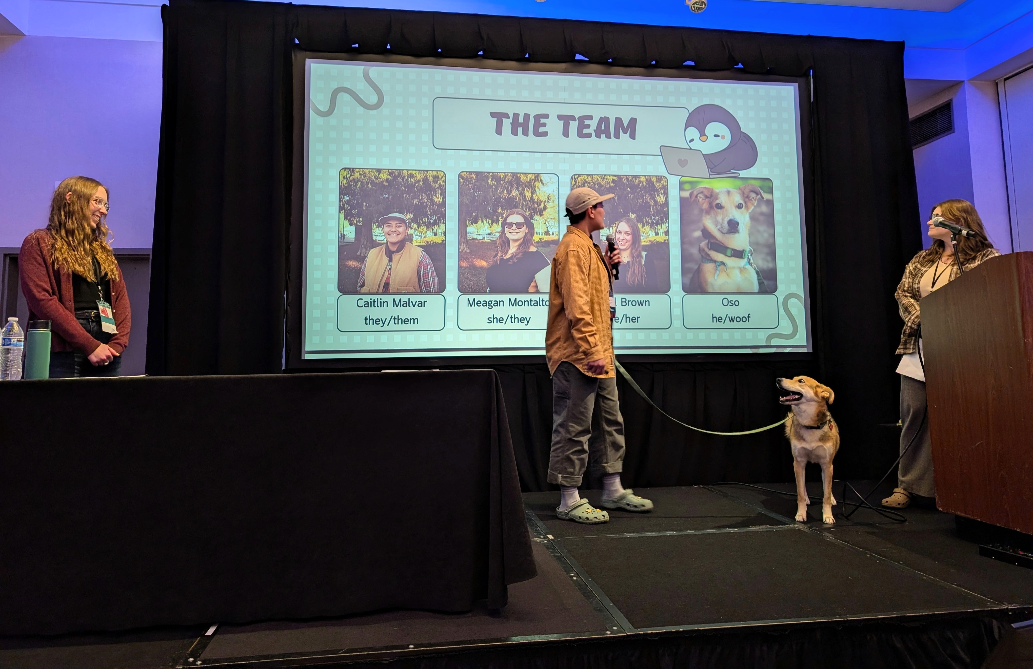 Pearl Brown, Caitlin Malvar, Meagan Montalto, and Oso the dog stand on a stage as they present at a conference.