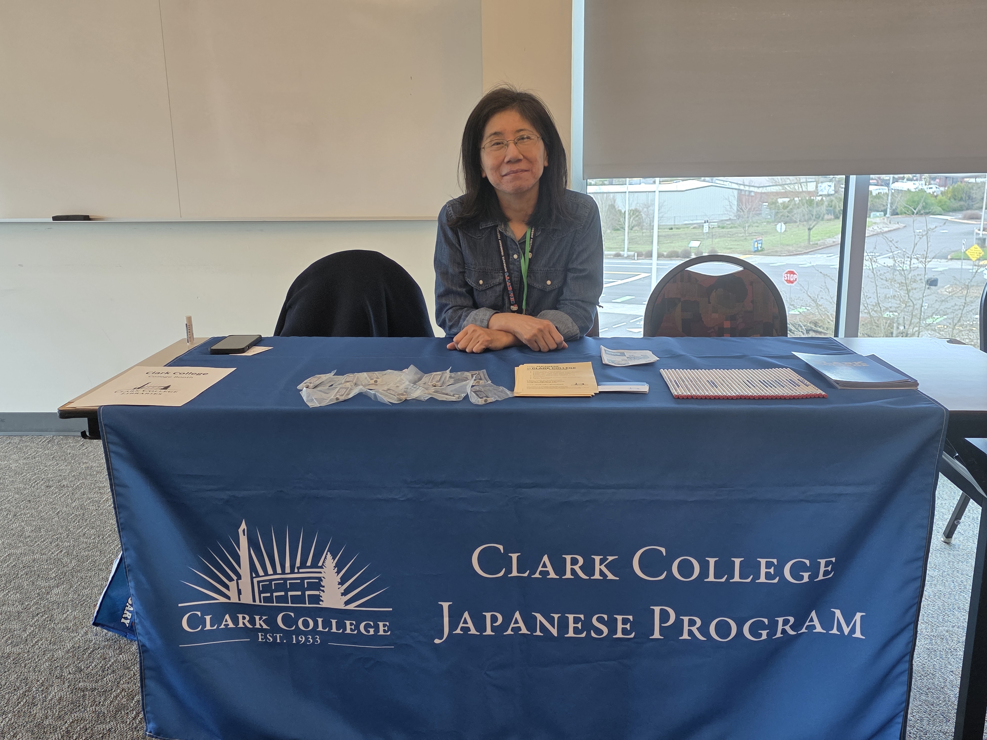 Michiyo Okuhara sitting at a vendor table with the Clark logo