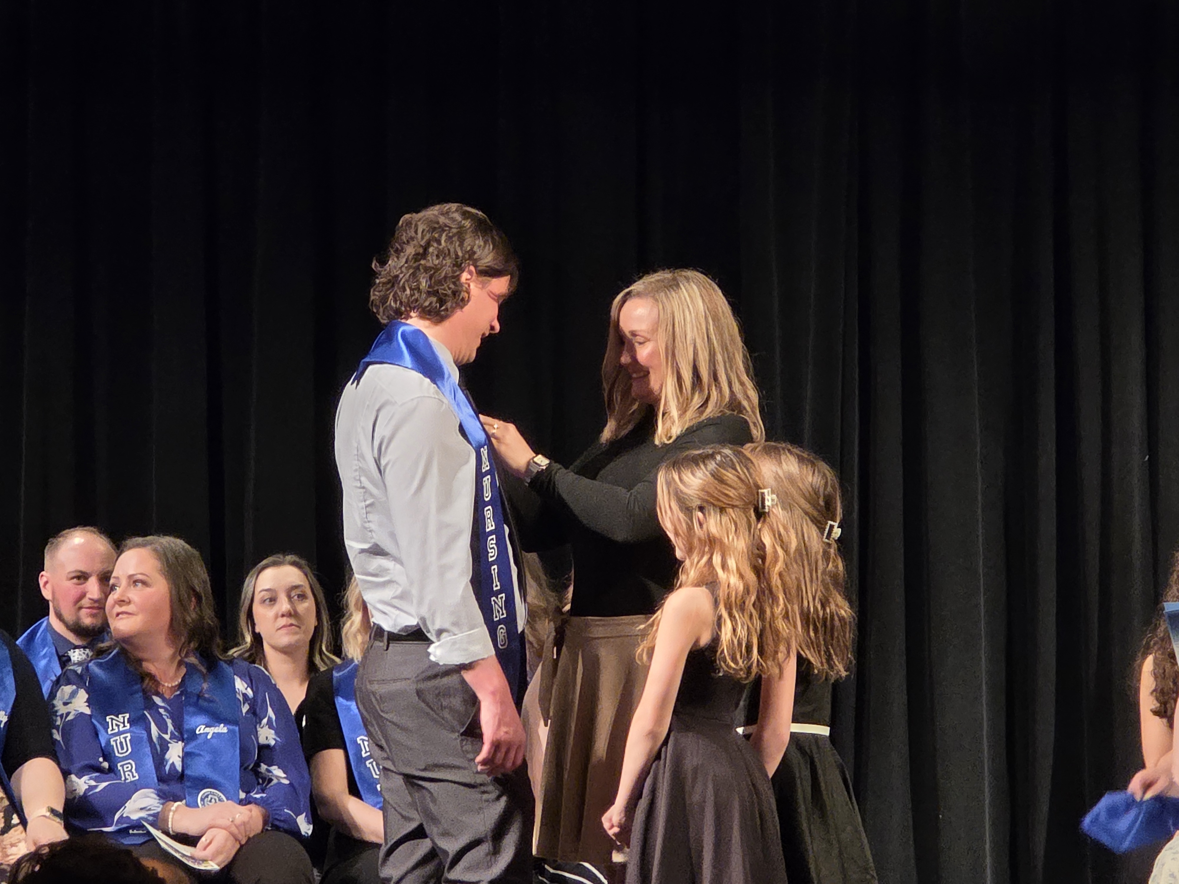 Nursing student receiving his nursing pin from his wife and daughters