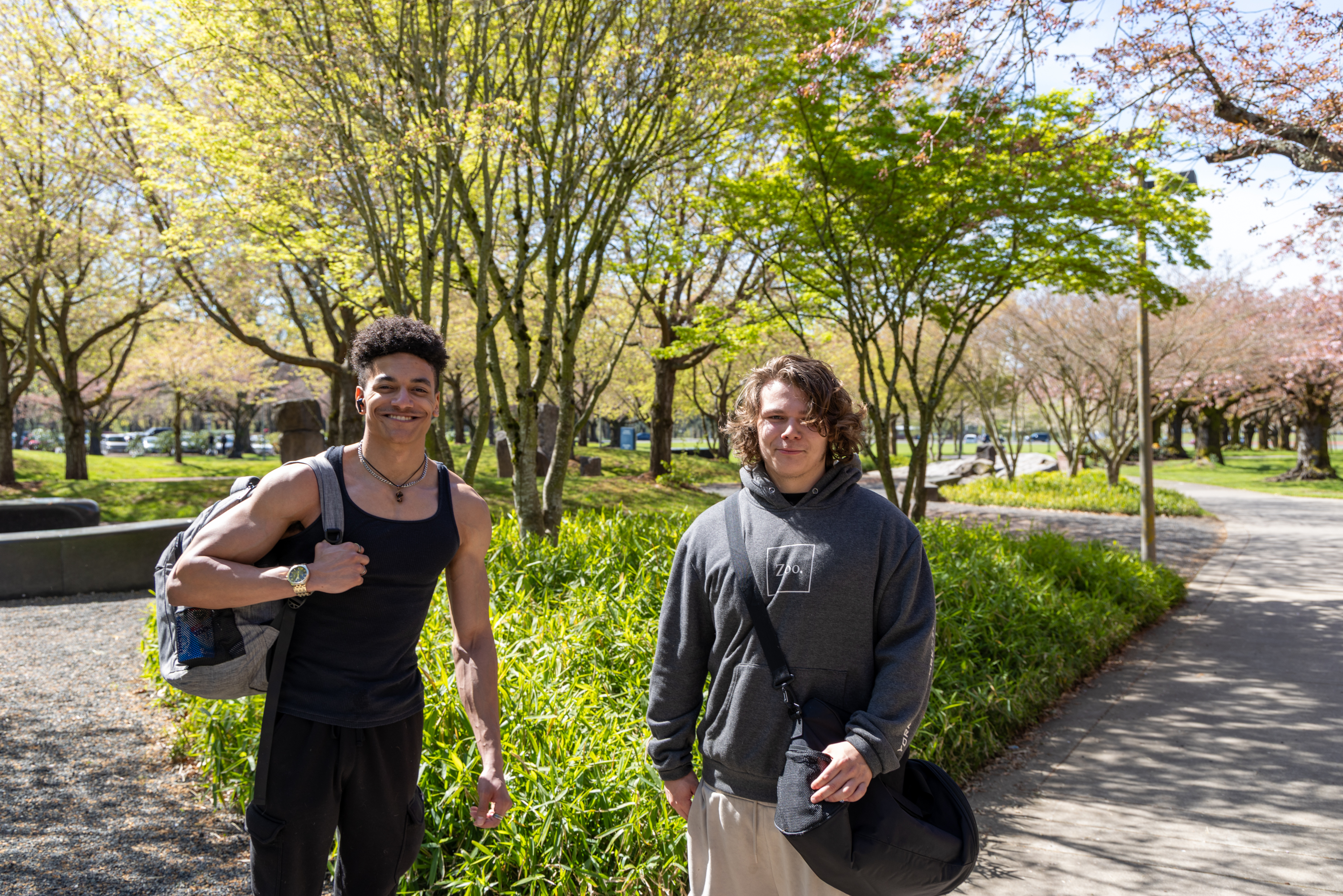 Two students smiling in front of a tree on campus