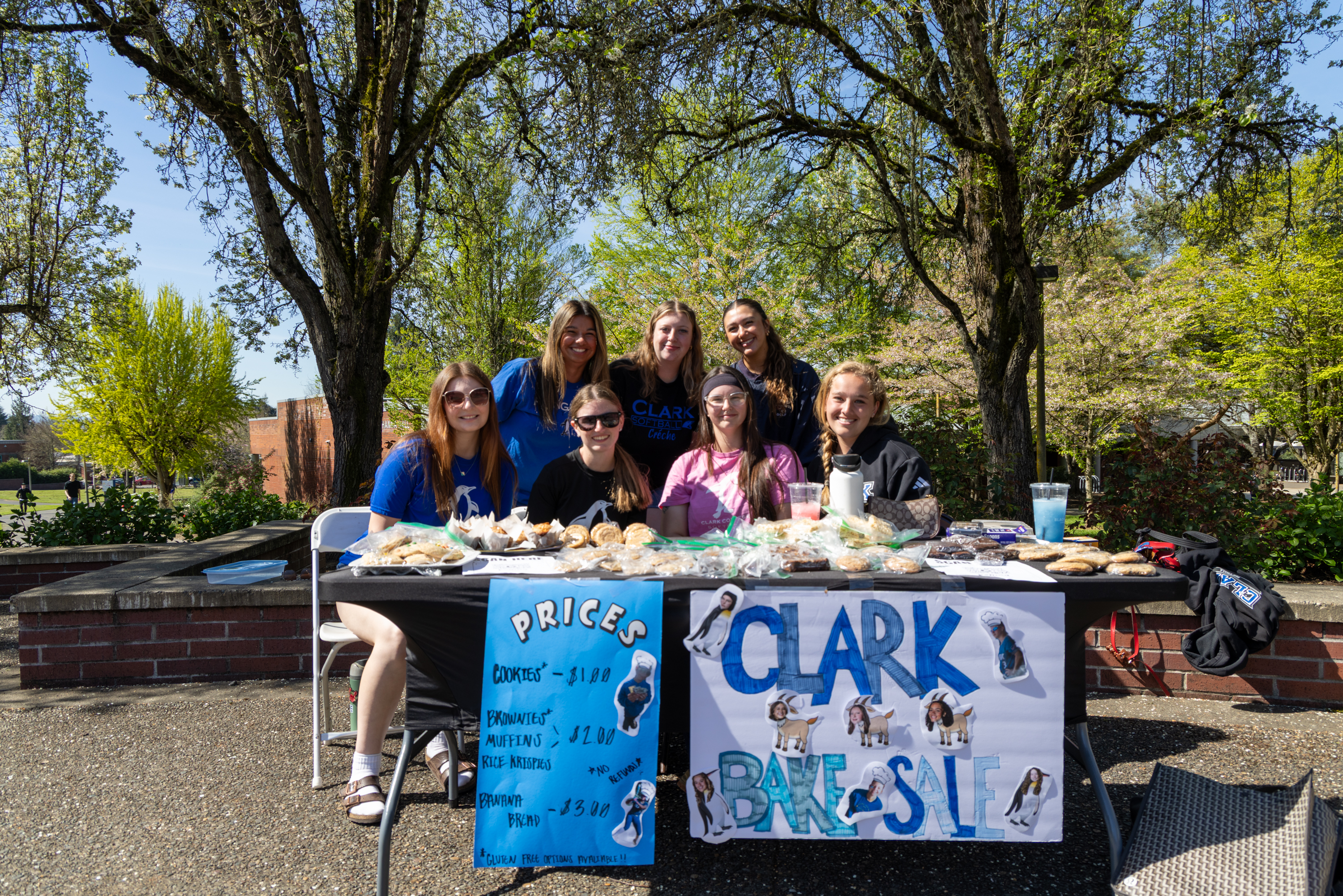 Softball team at table on campus during bake sale
