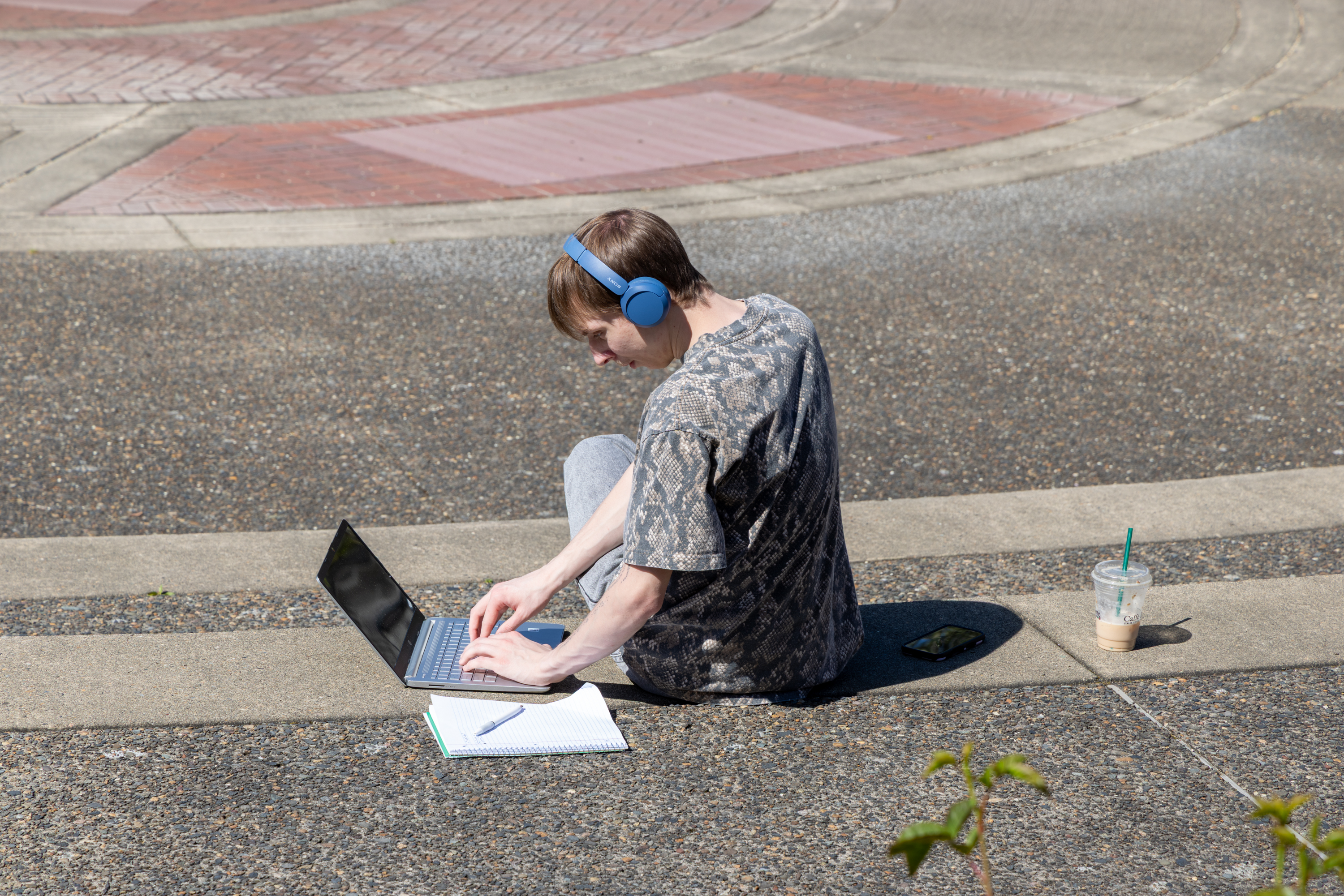 Student outside wearing headphones on laptop