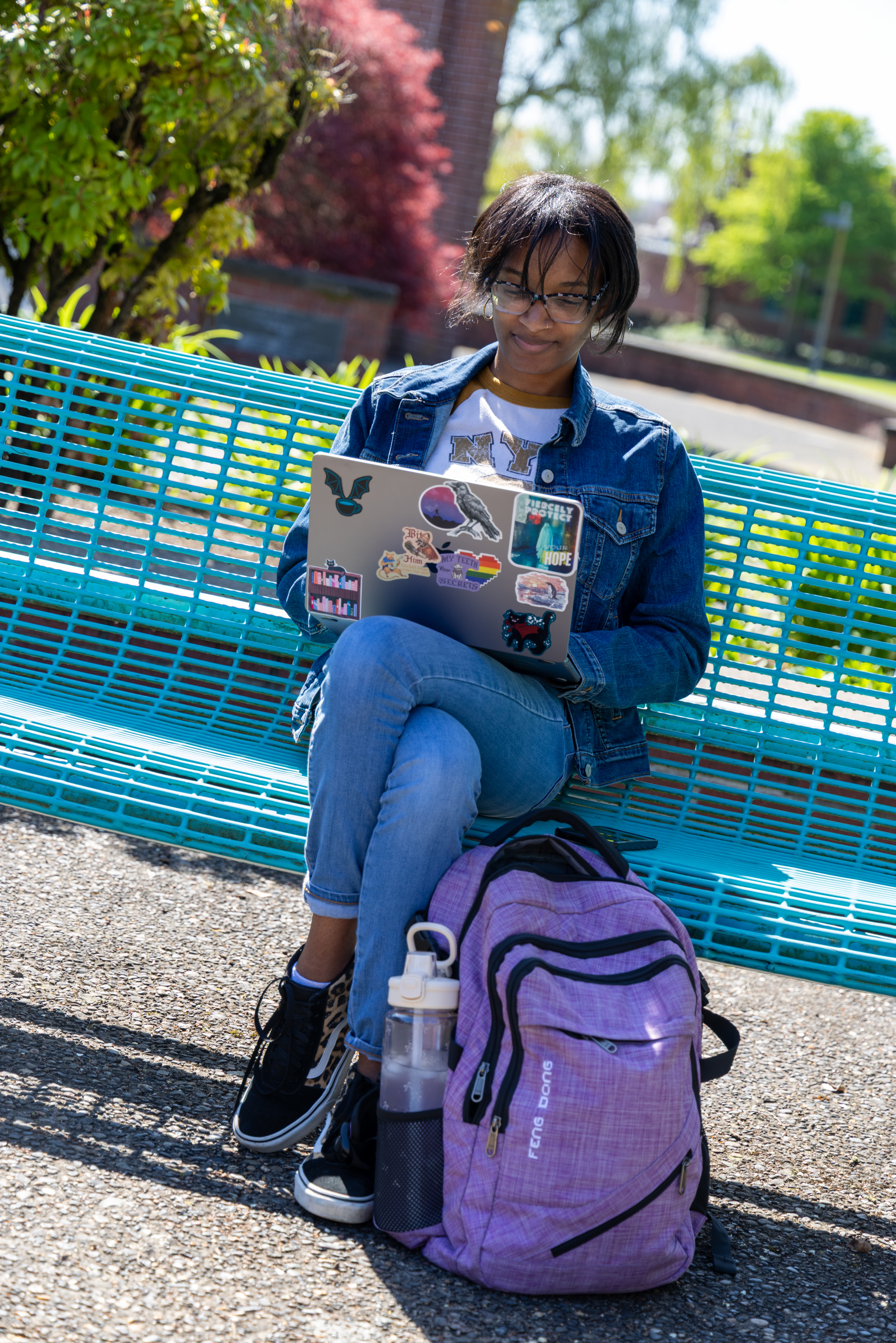 Student on a bench on campus looking at laptop