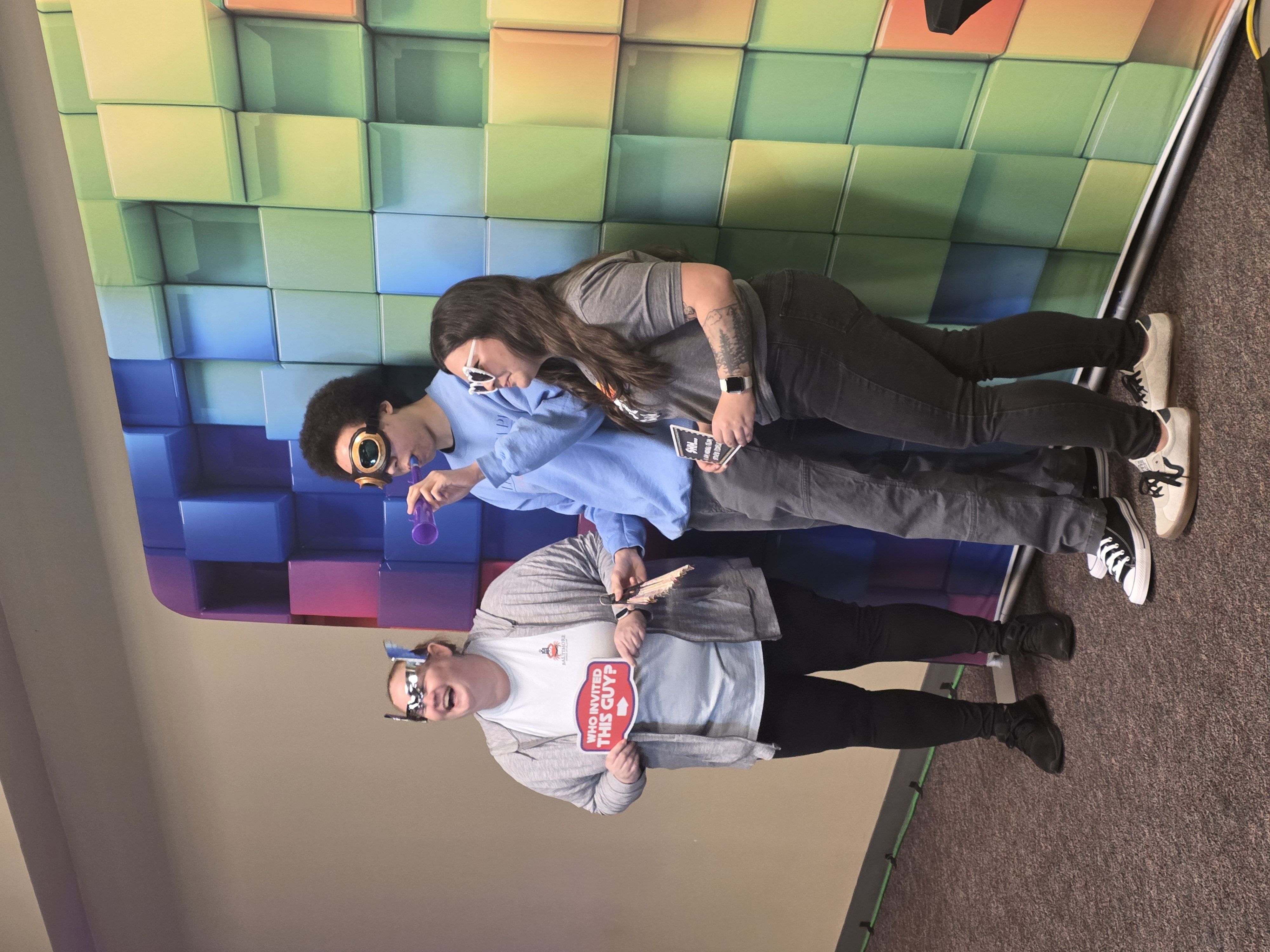 Students laughing in front of a photobooth with a colorful background