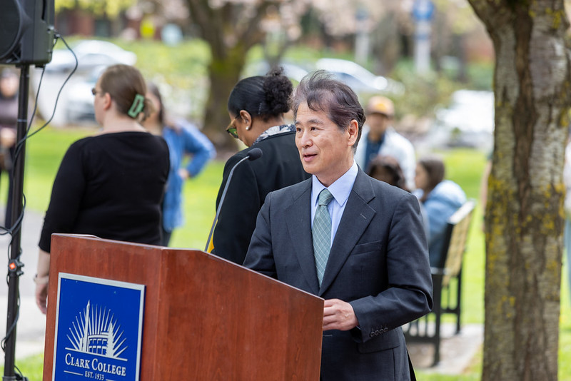 Consul General Ken&nbsp;Todoriki at a podium under cherry blossom trees