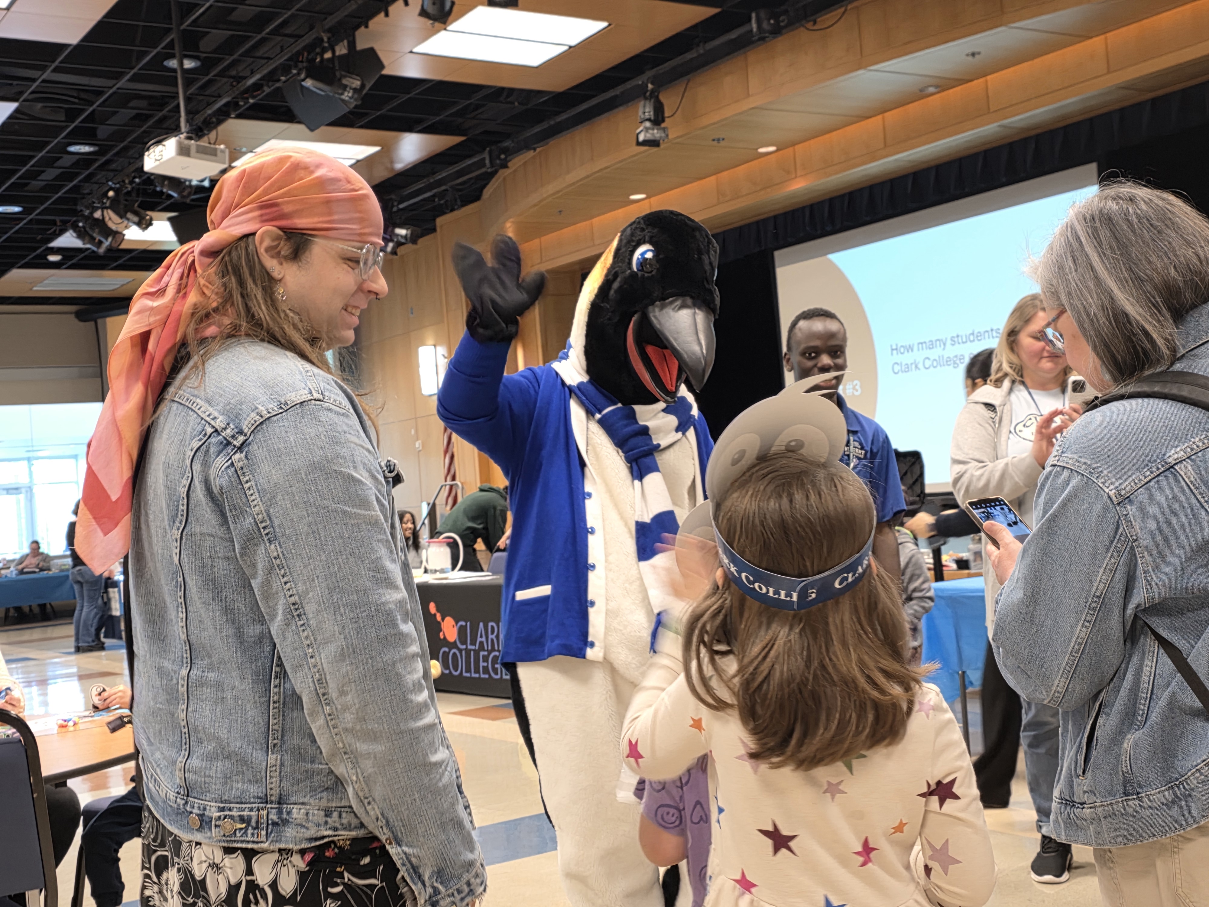 A young girl wearing a paper penguin crown waves at Oswald