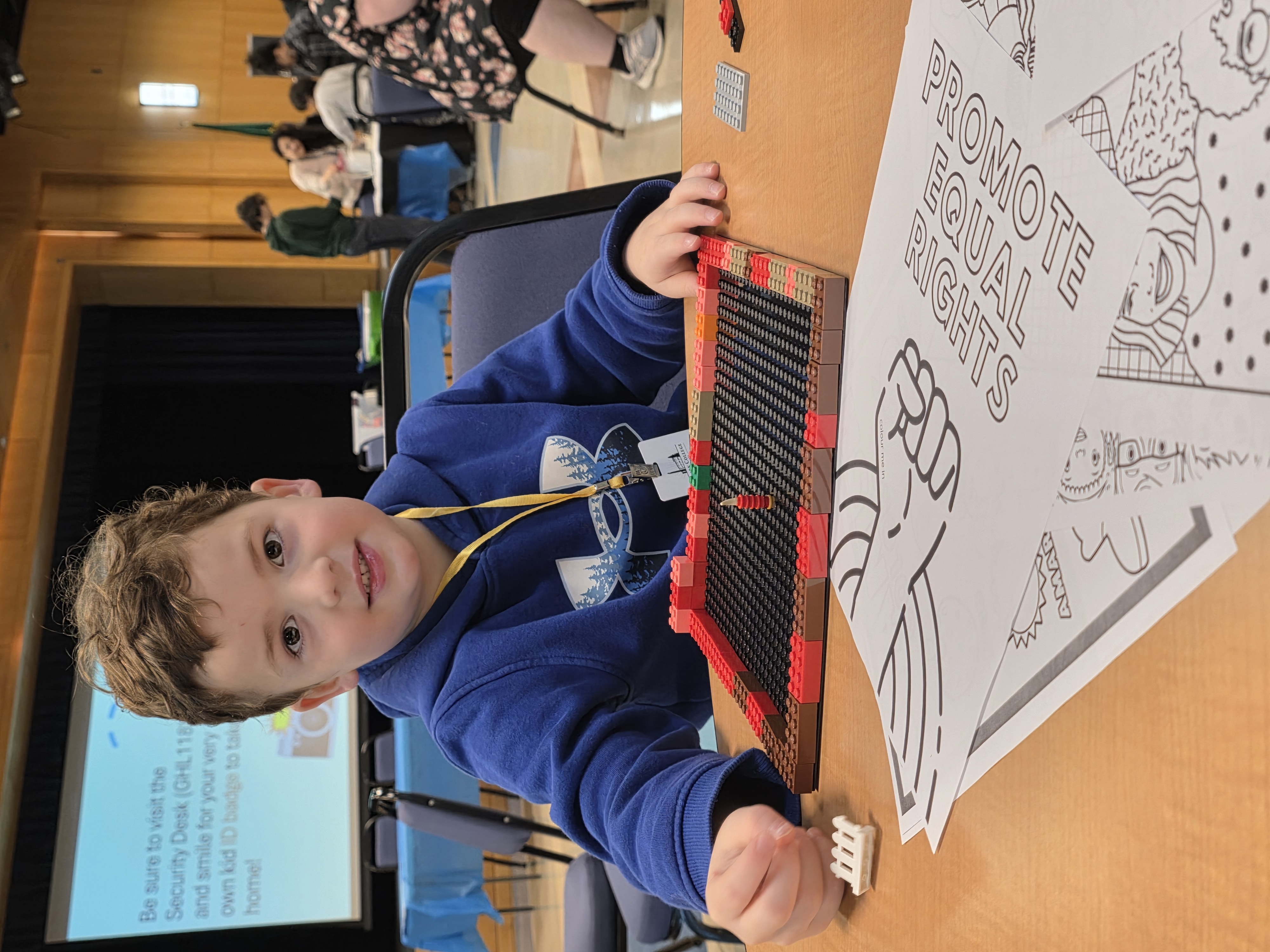 Child smiles at the camera as he builds a house with legos