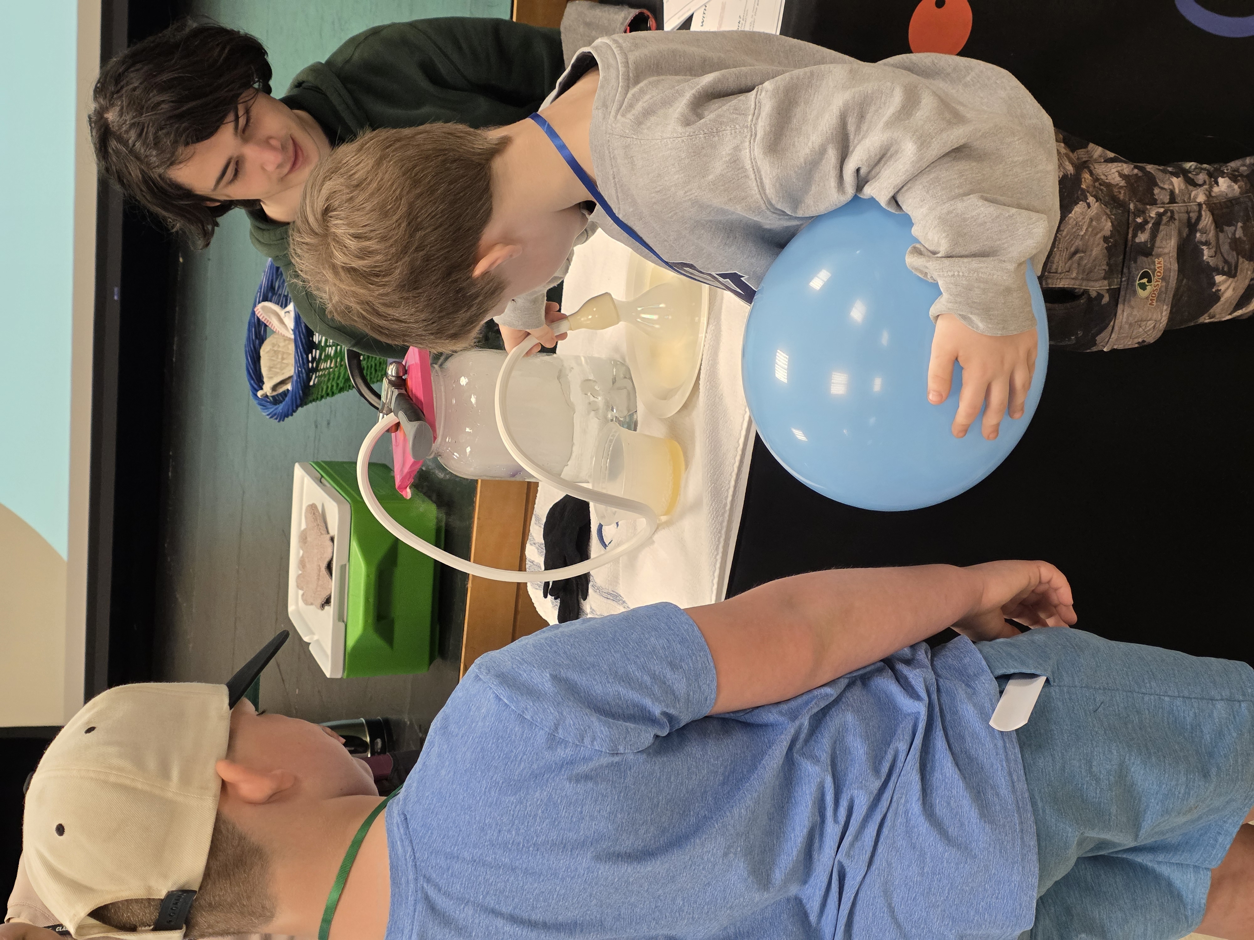 Two young boys play with a machine that creates fog-filled bubbles