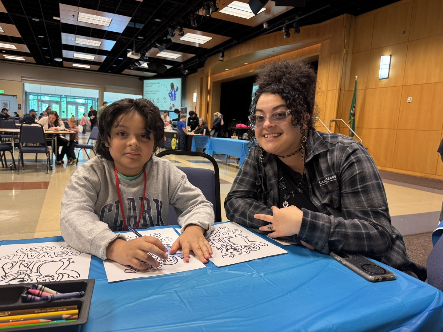 Child and an adult sit at a table with coloring pages