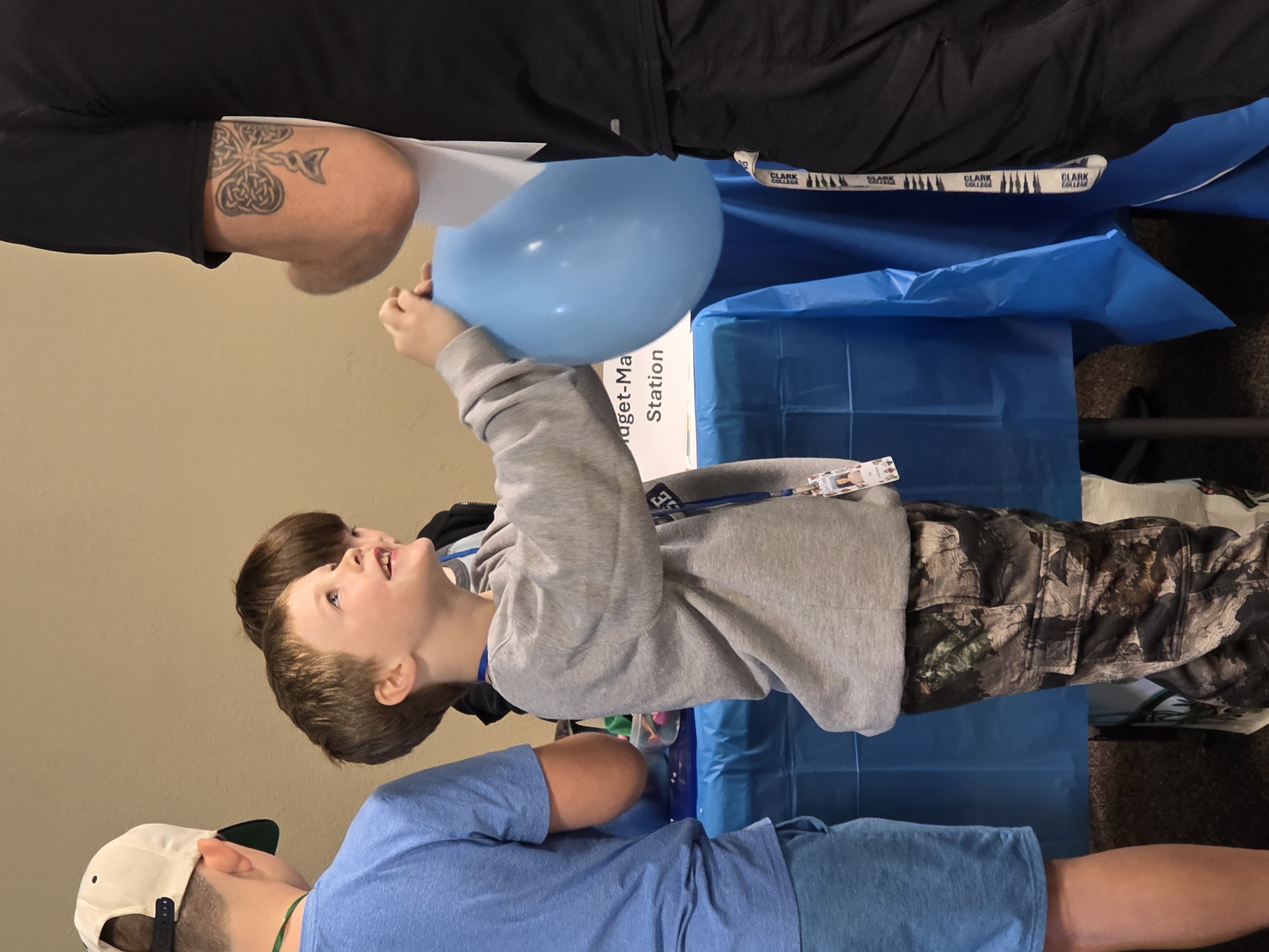 Young boy holds a blue balloon and smiles up at his father