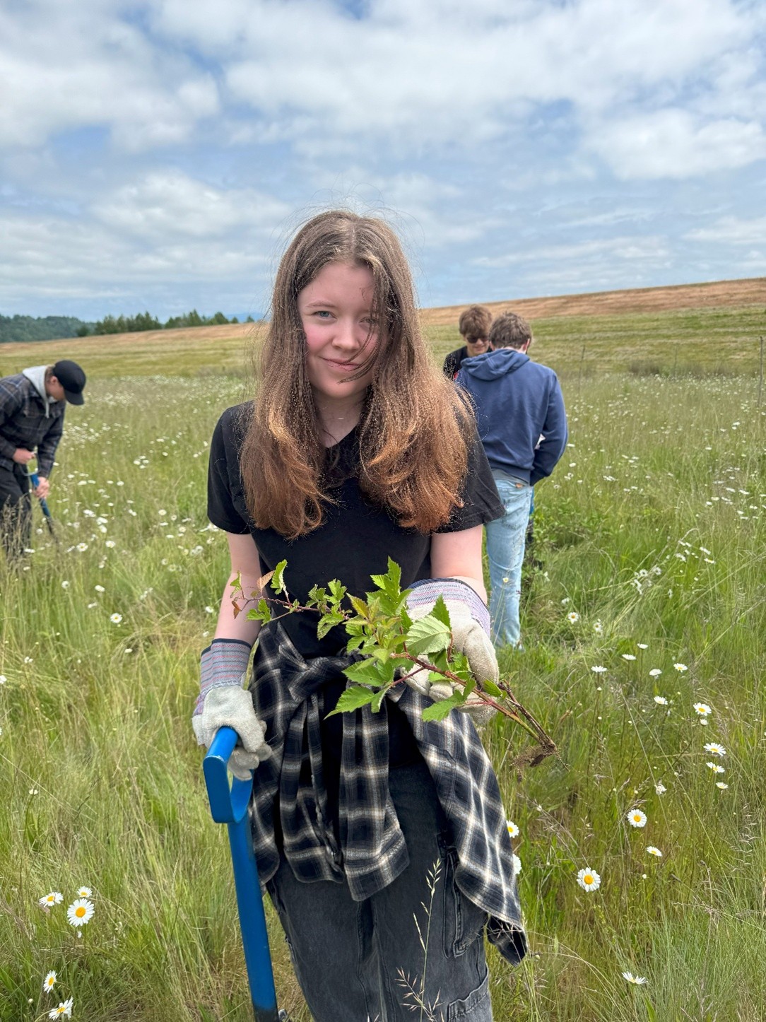 A student holds up a piece of blackberry plant to the camera