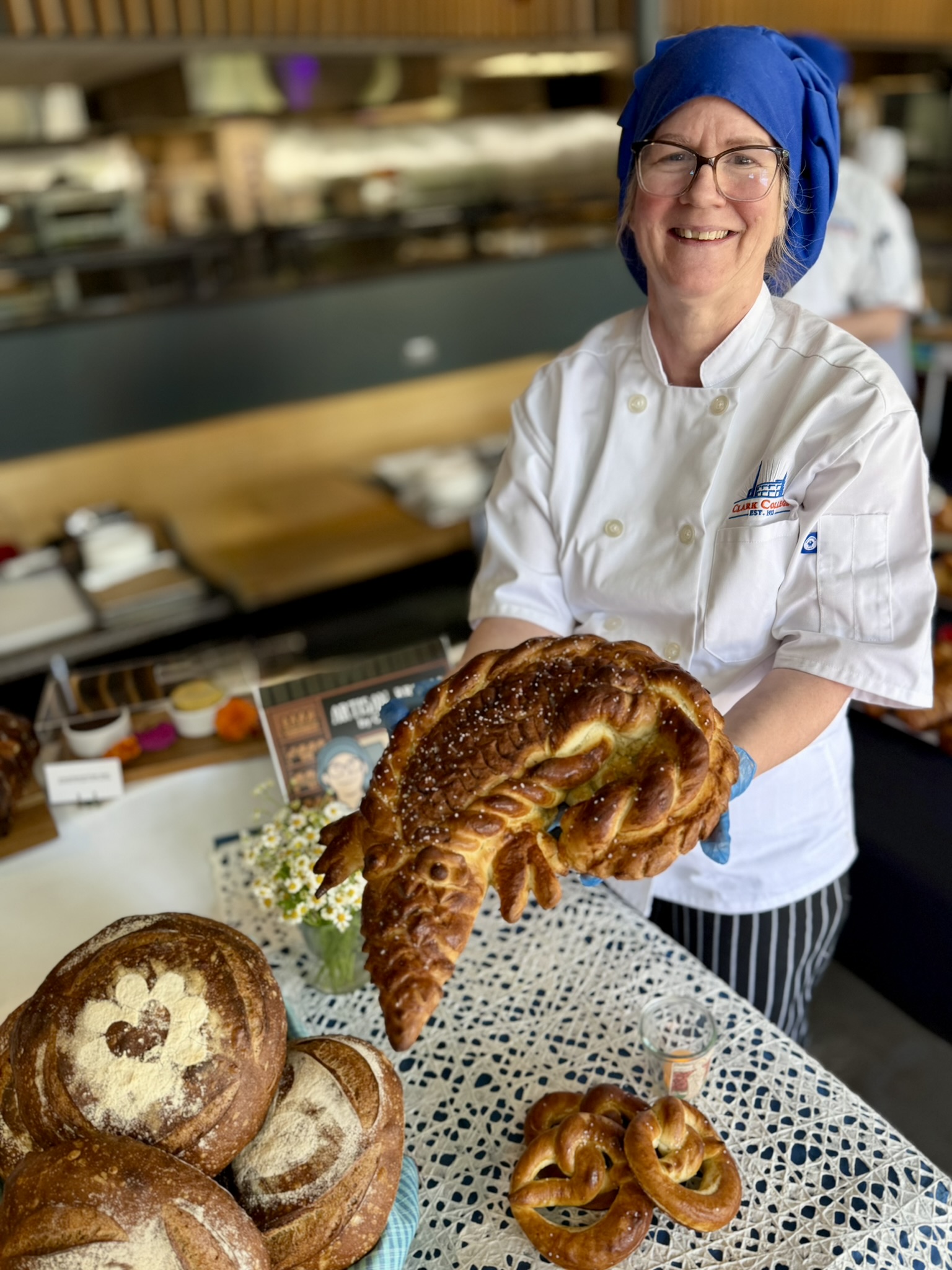 Baking student Christy holding up her gator shaped loaf of bread