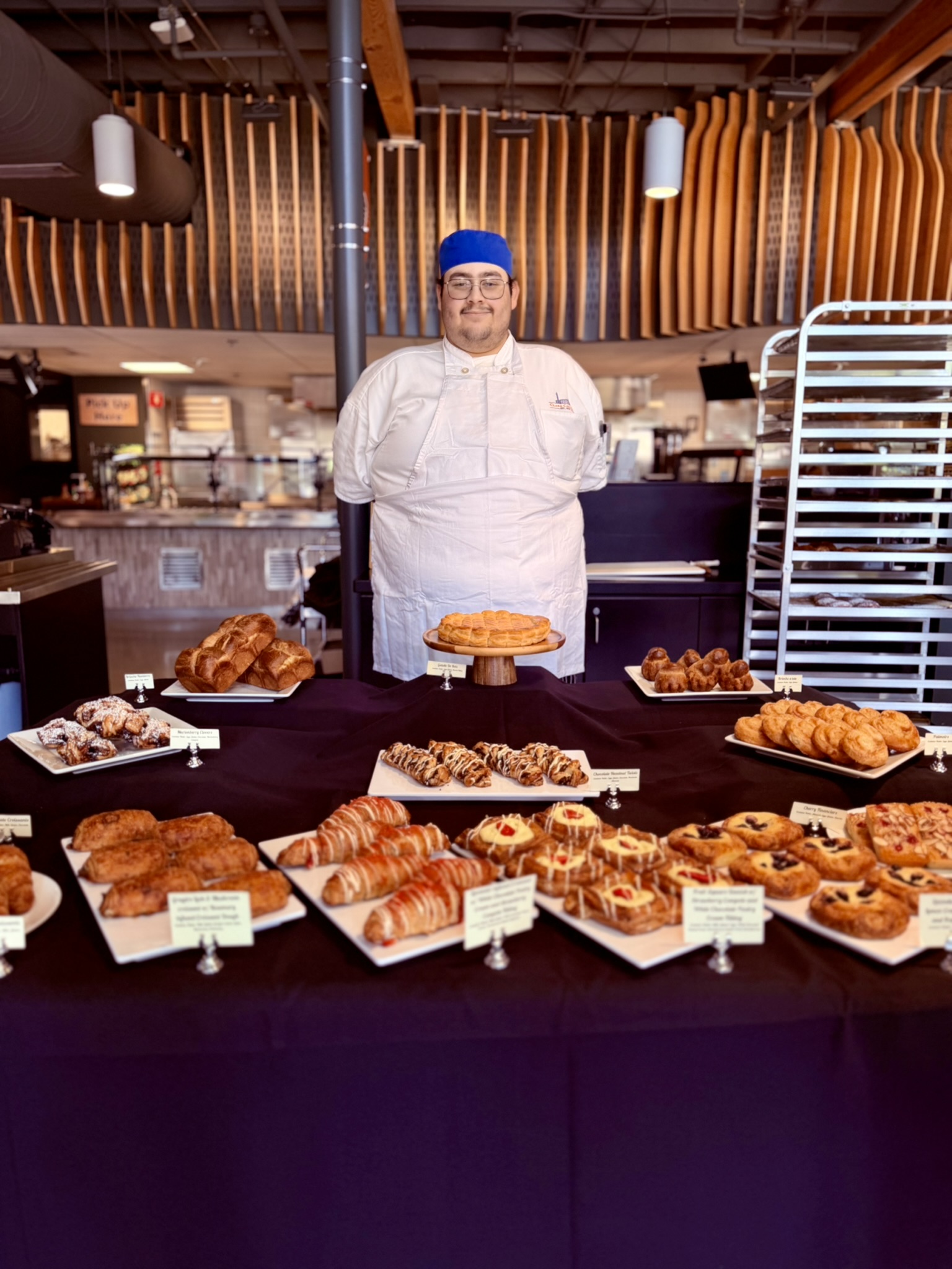 Baking student stands behind his table of baked goods