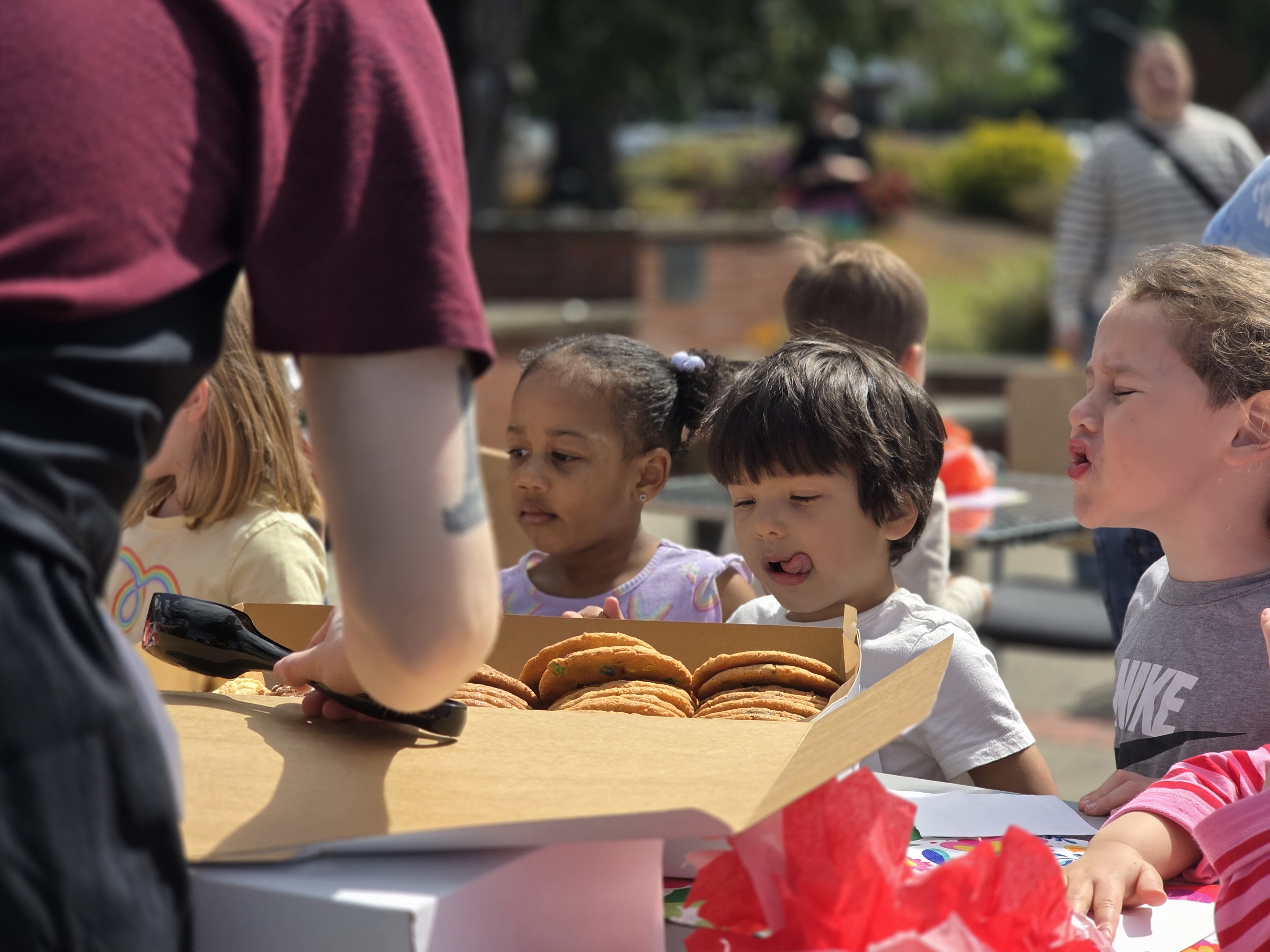 Little boy licking his lips next to a box of cookies