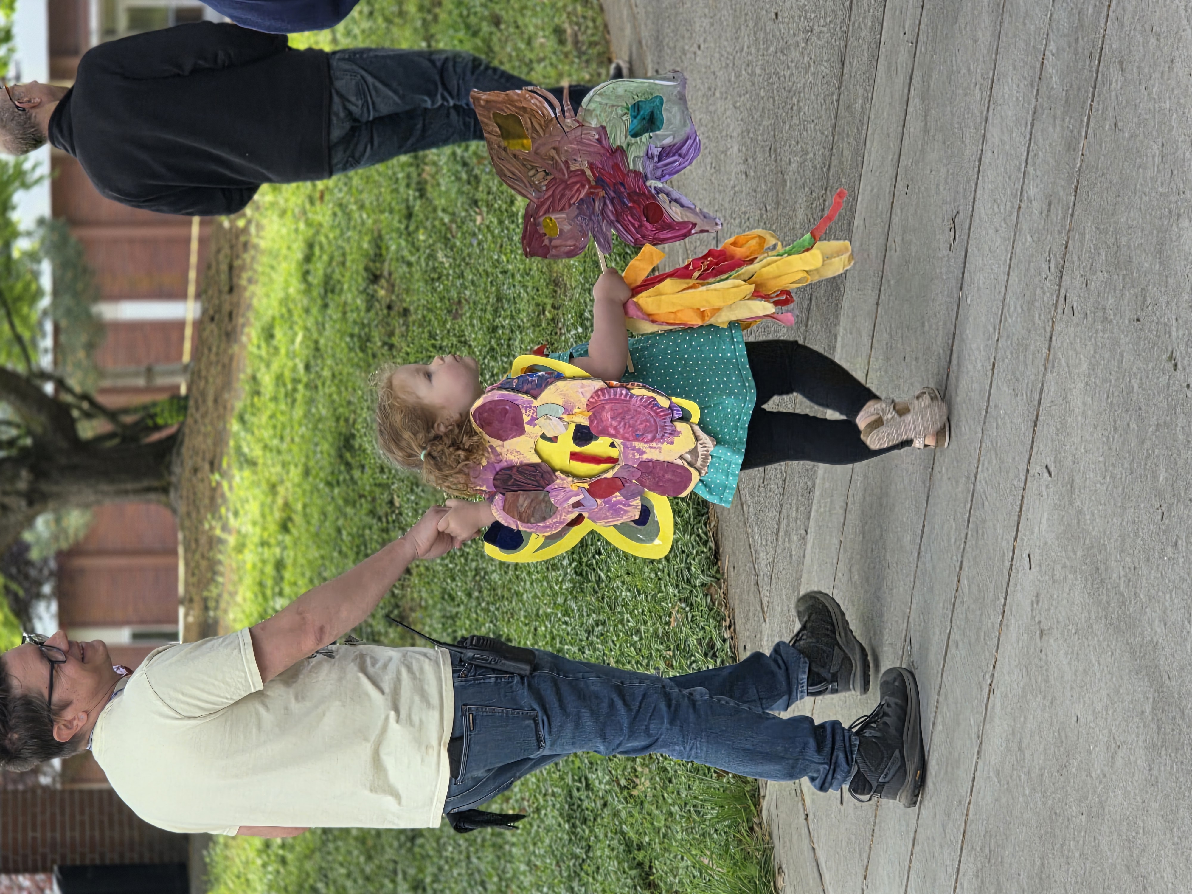 Little girl wearing butterfly wings made out of cardboard, holding a woman's hand