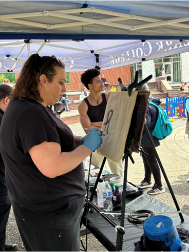 An airbrush artist begins painting a custom tote bag for a student