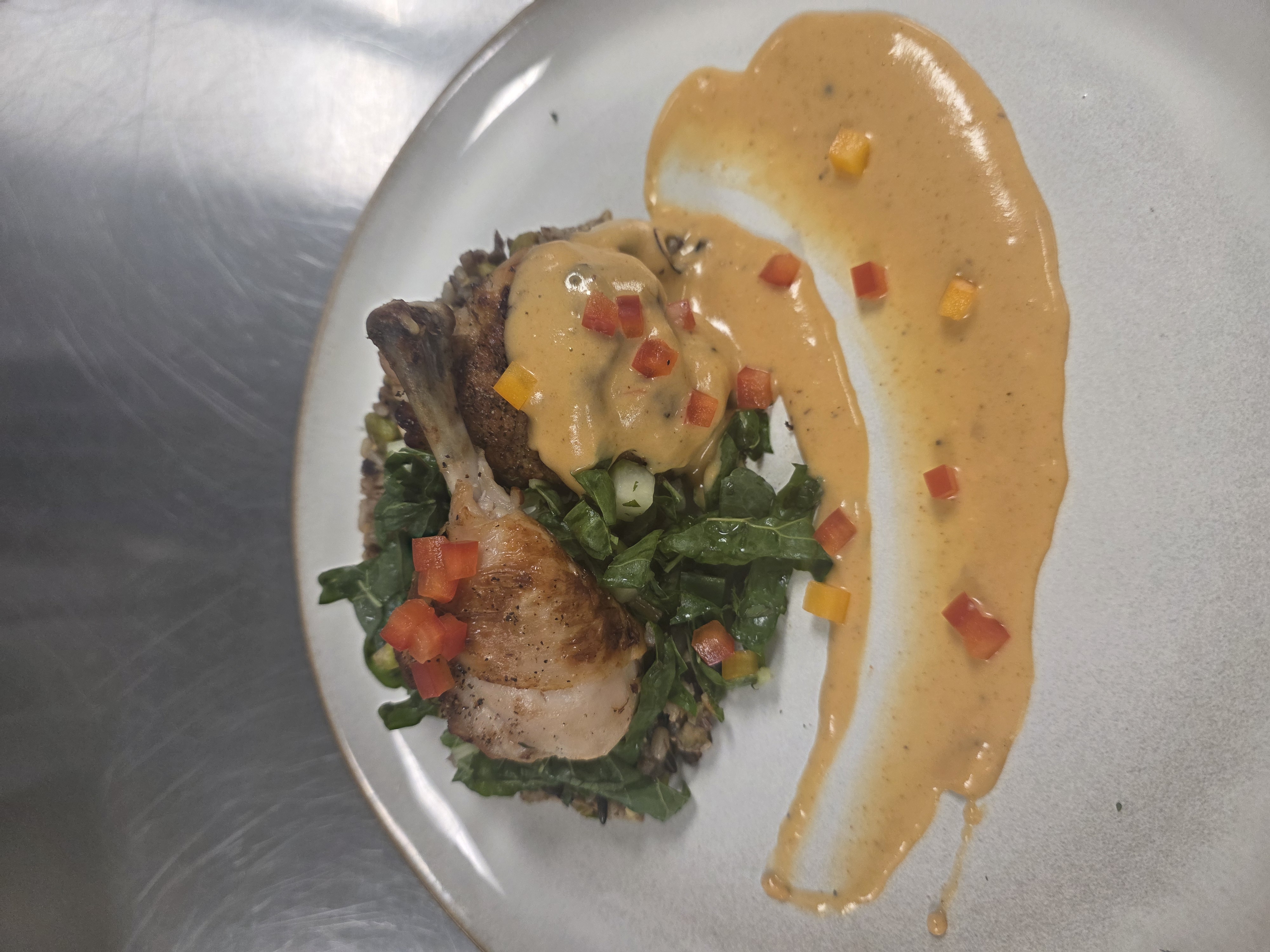 Chicken, sauce, rice, and vegetables arranged on a plate