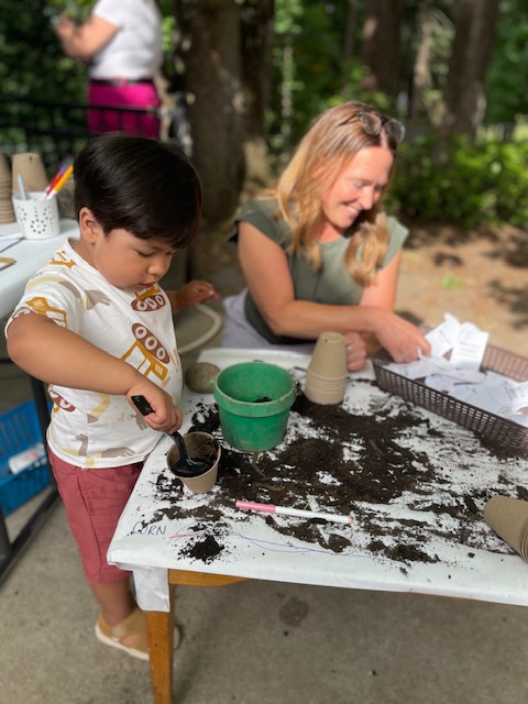 Child pouring soil into a green plastic bucket