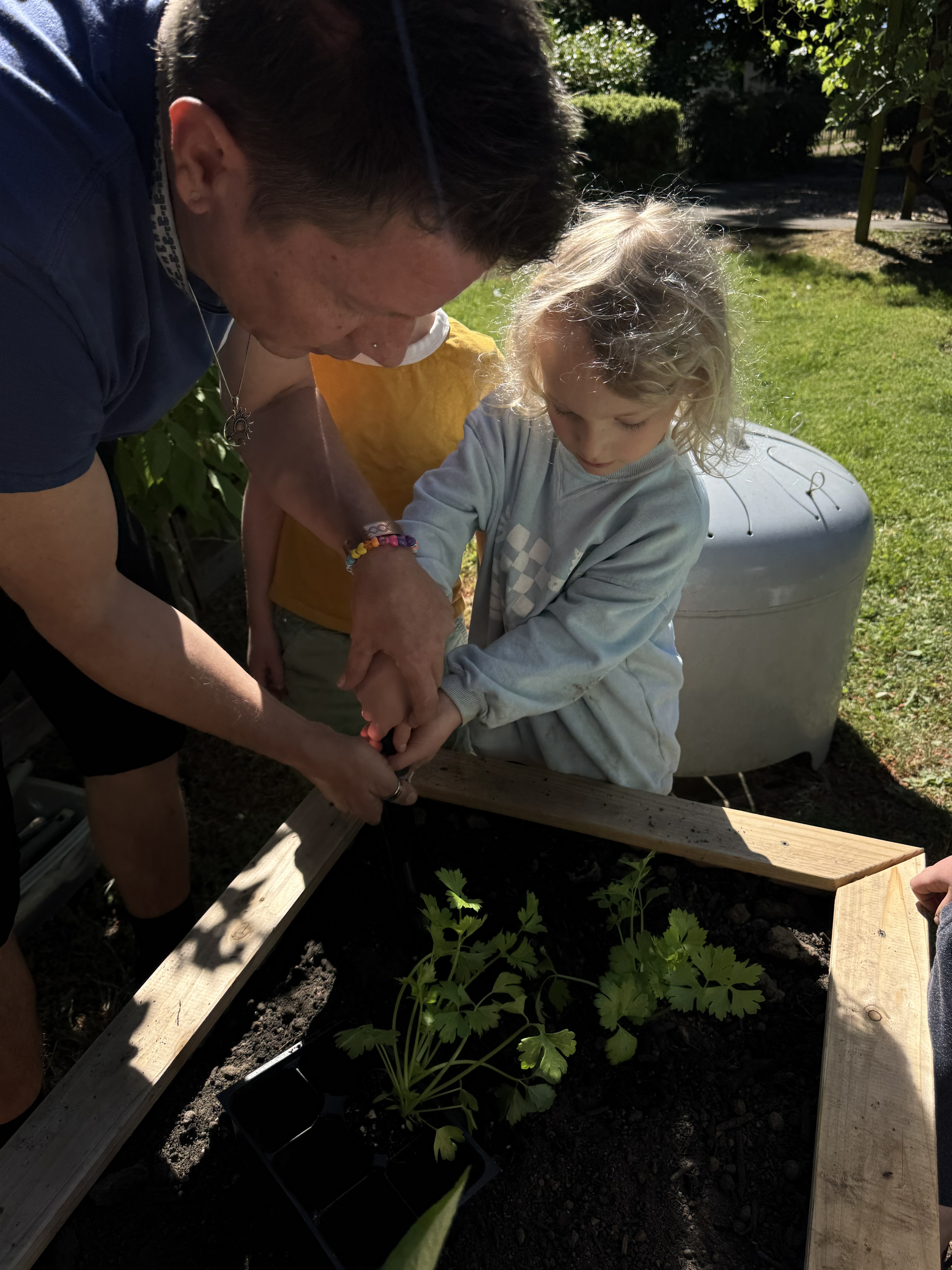 Outdoor instructor helps little girl dig in soil