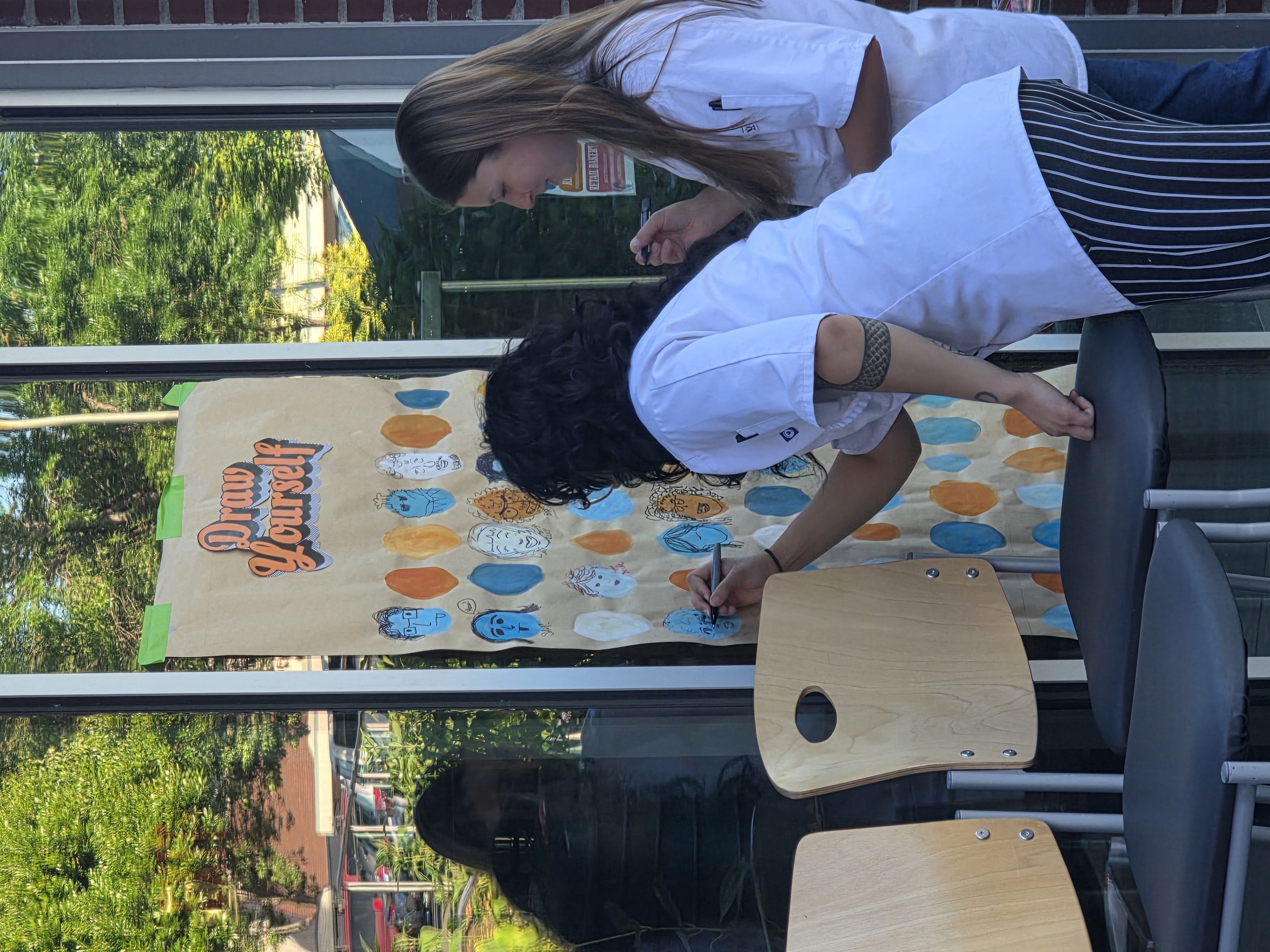Two event attendees draw on brown butcher paper