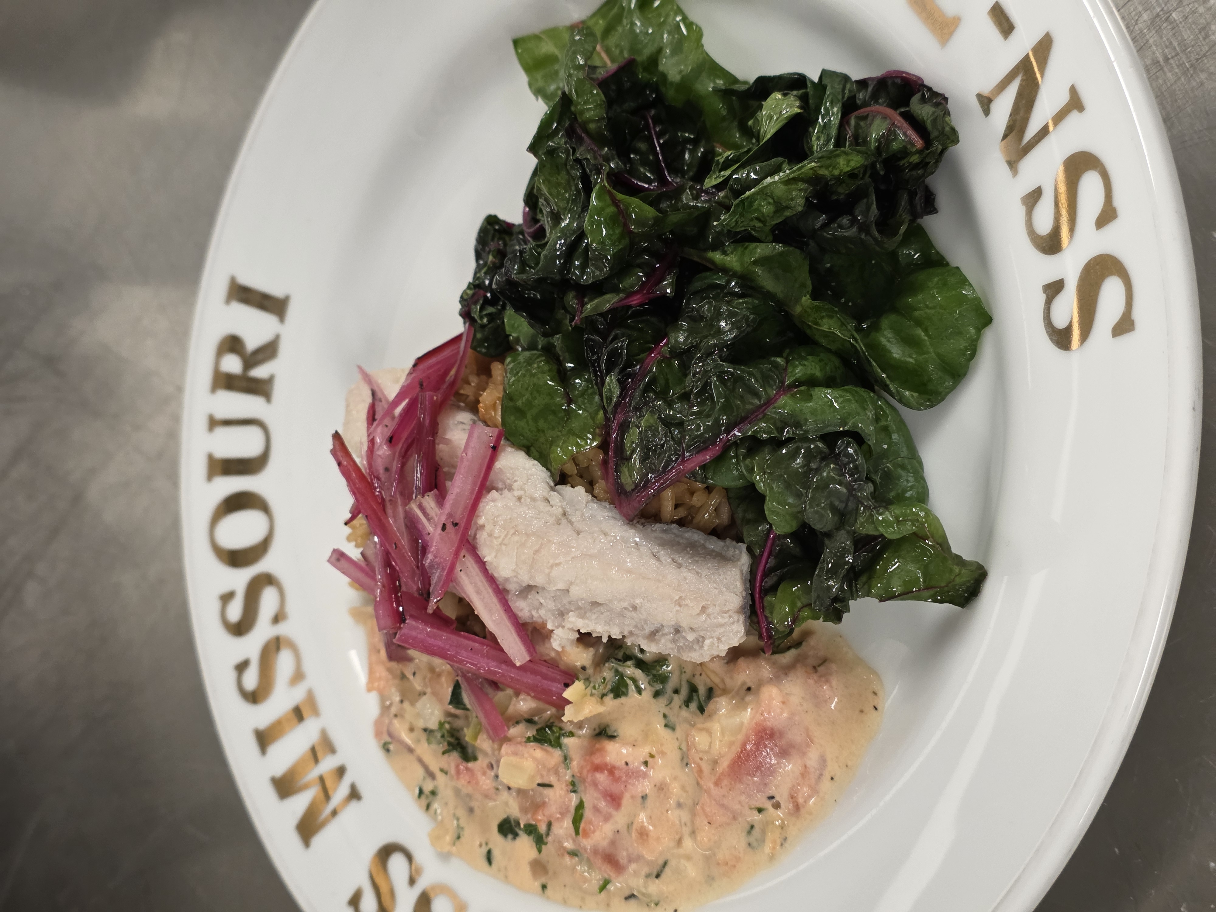 Poached fish with greens and side dish on a US Navy themed plate