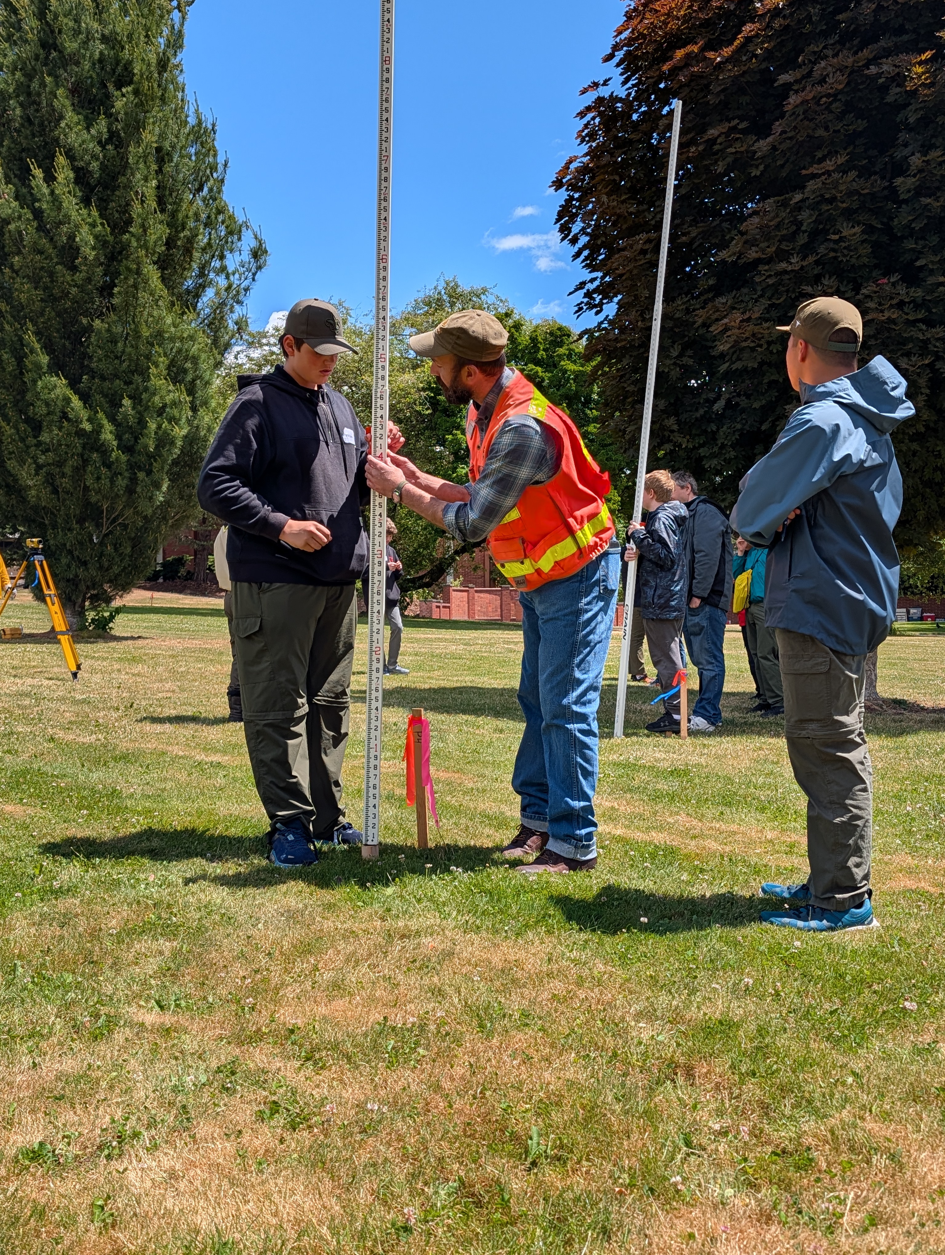Scout and instructor use a grade rod to measure elevation