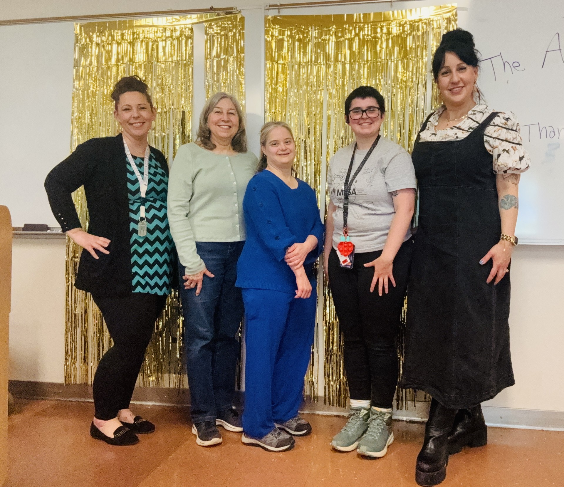 People standing in front of a sparkly background in a classroom