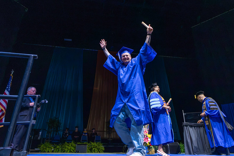 Graduate celebrates while walking across the stage at commencement